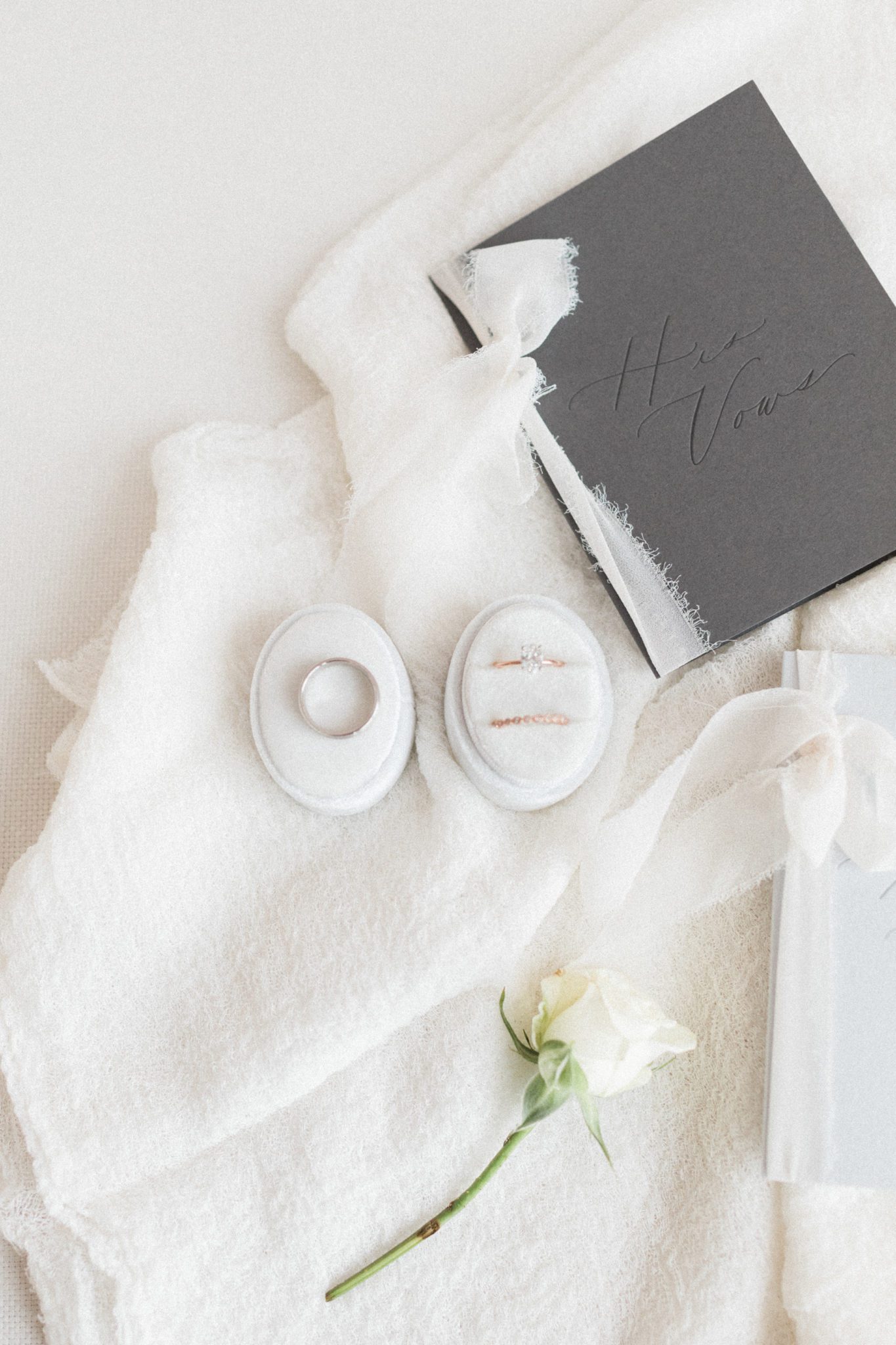 Monochromatic wedding inspiration with a white velvet ring box and charcoal vow books