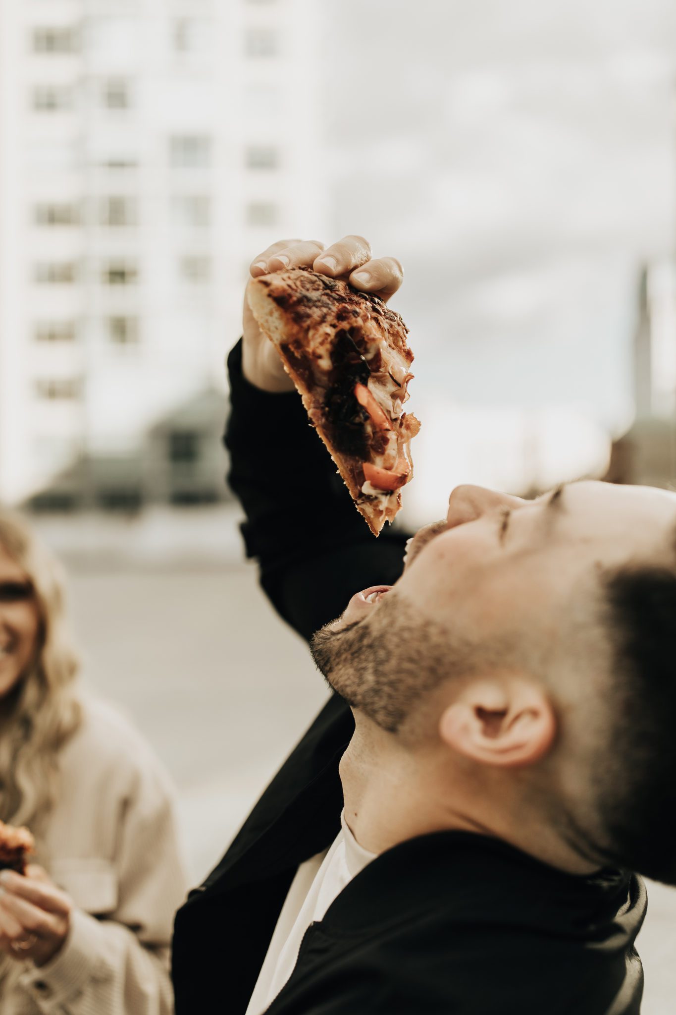 Man eating pizza on a rooftop
