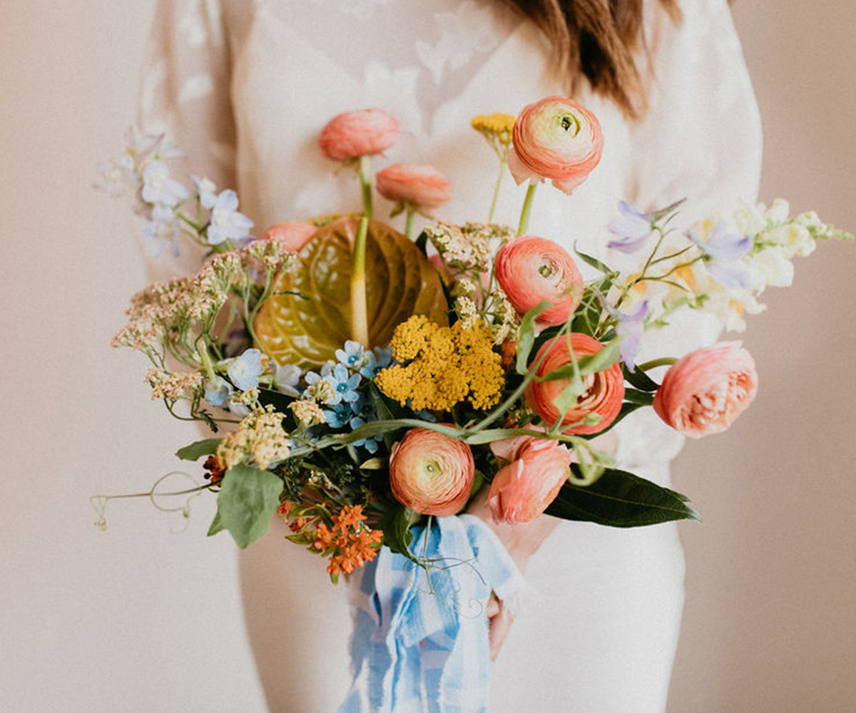 Peach and coral bridal bouquet tied with a blue silk ribbon