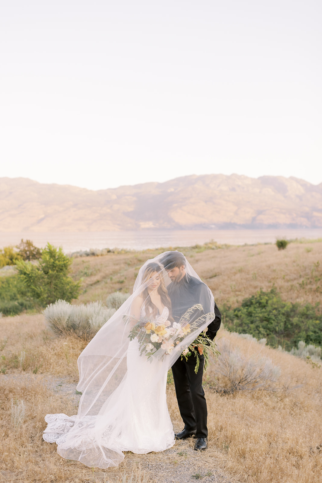 Veil portrait of bride and groom at sunset