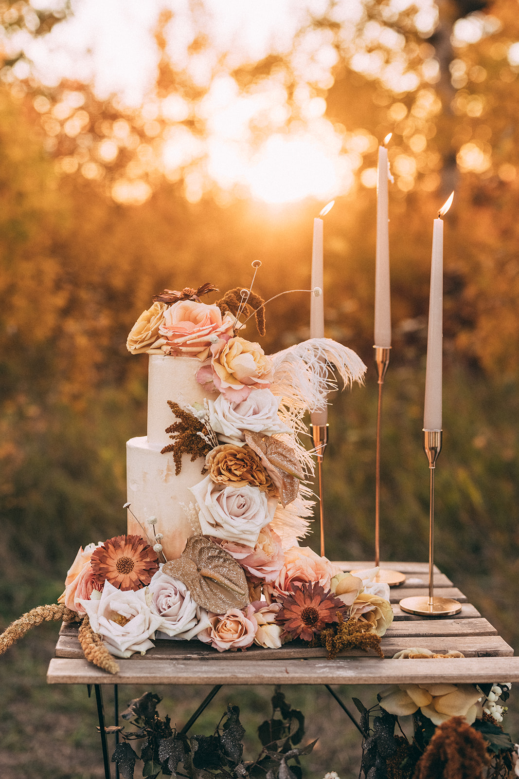 Boho wedding cake at sunset adorned with fall florals
