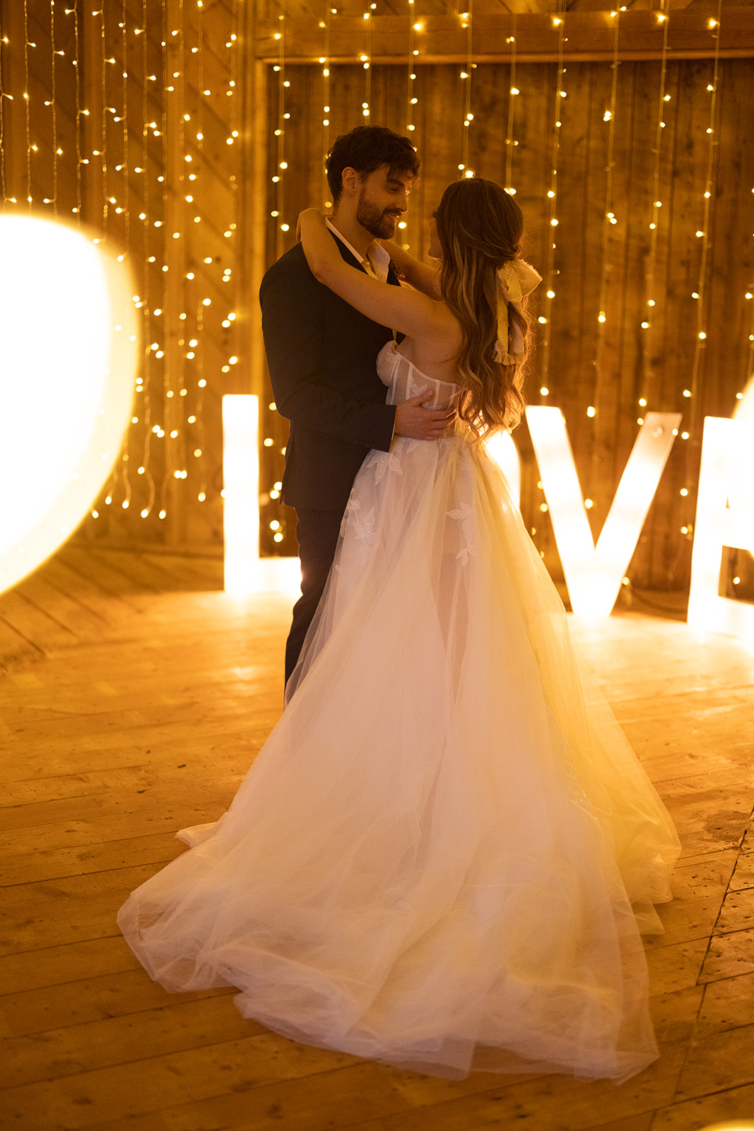 Romantic first dance under twinkle lights in a barn