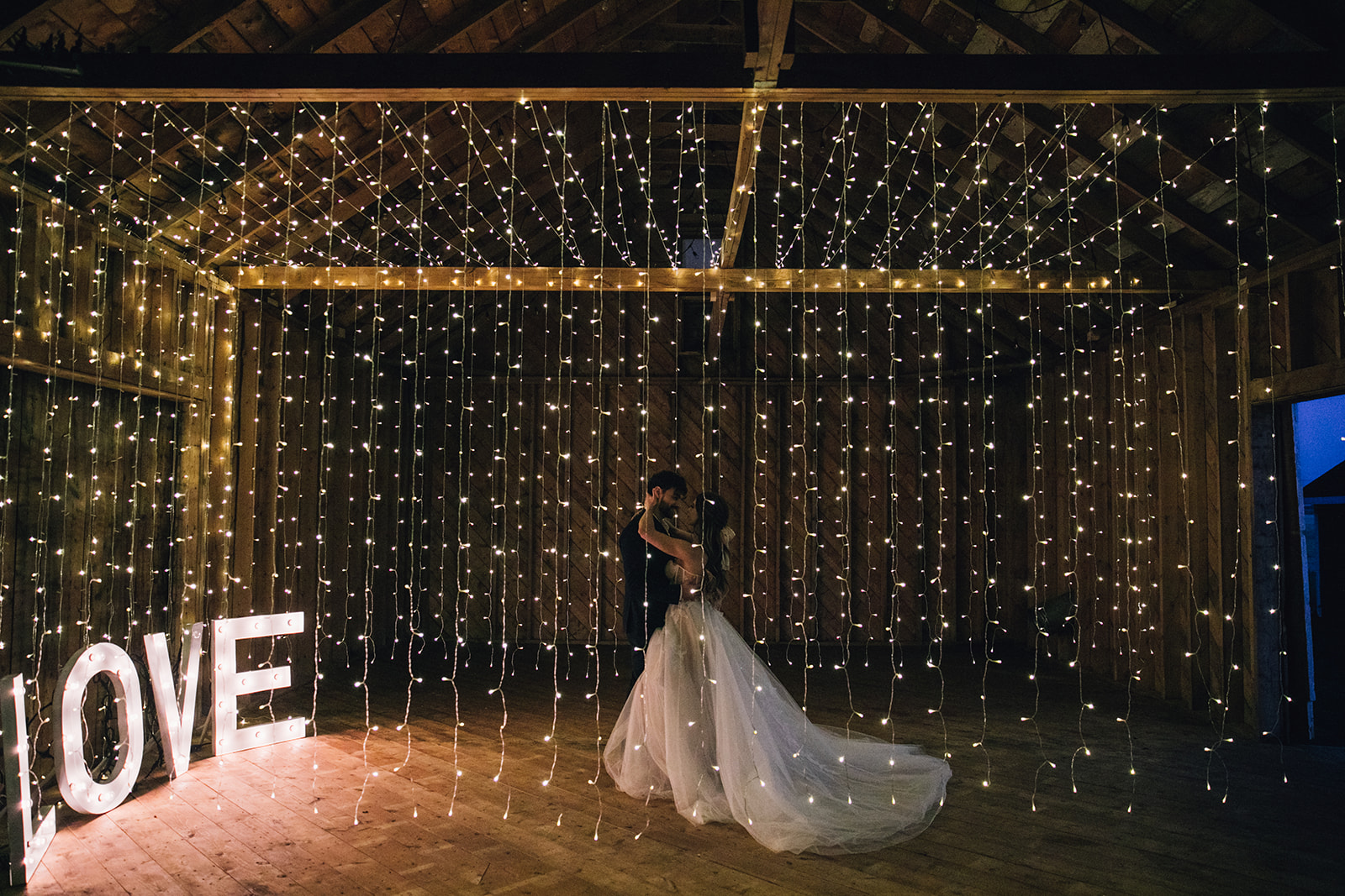 Romantic first dance in a barn with twinkle lights