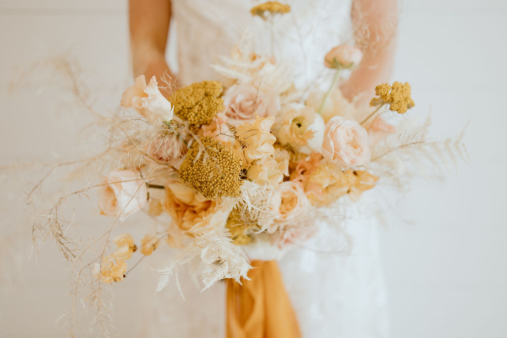 Fall wedding bouquet with a mix of fresh and dried florals in cream and ochre hues