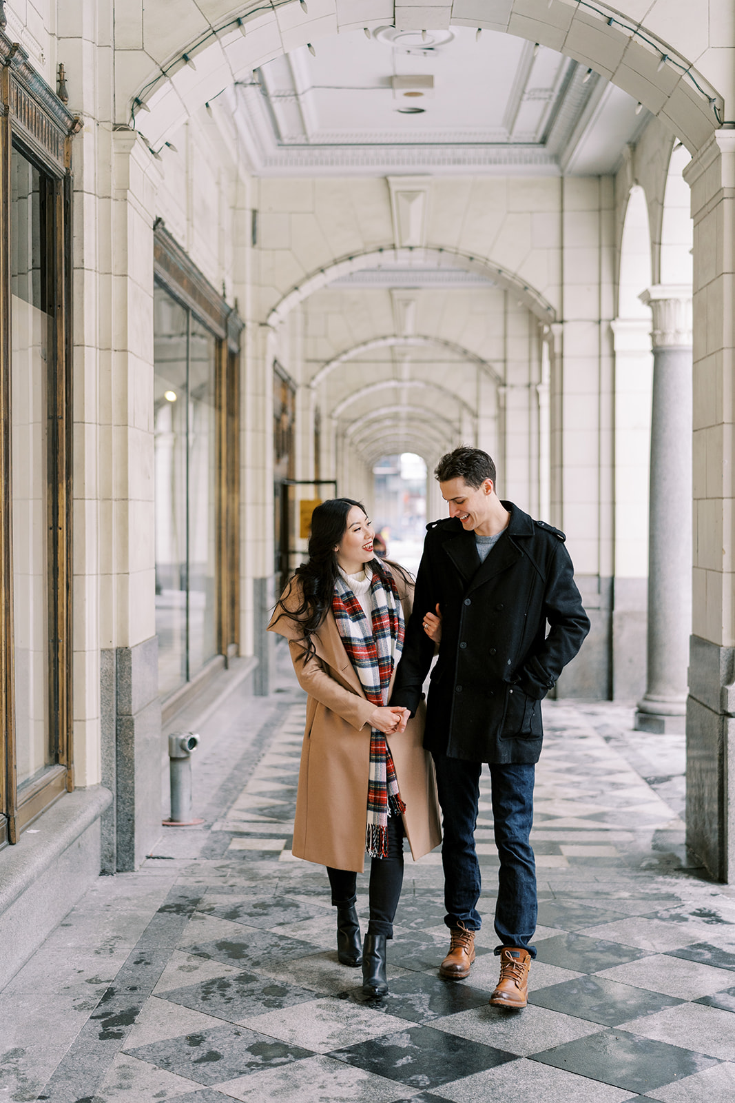 Calgary couple posing and walking in front of the Hudson arches on Stephen Ave, for their downtown engagement session.
