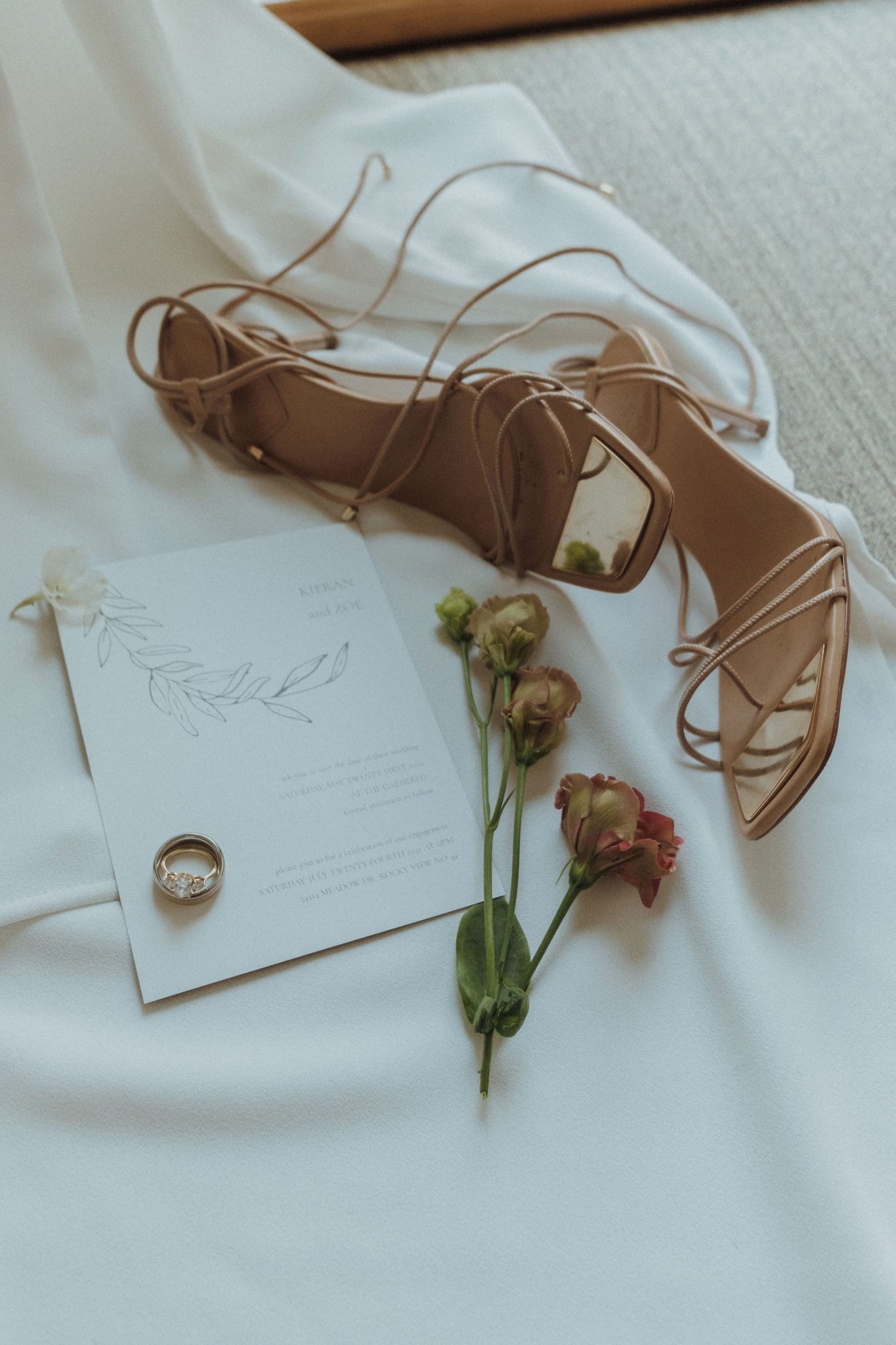 Bridal details of heels and custom wedding invitation with dried roses