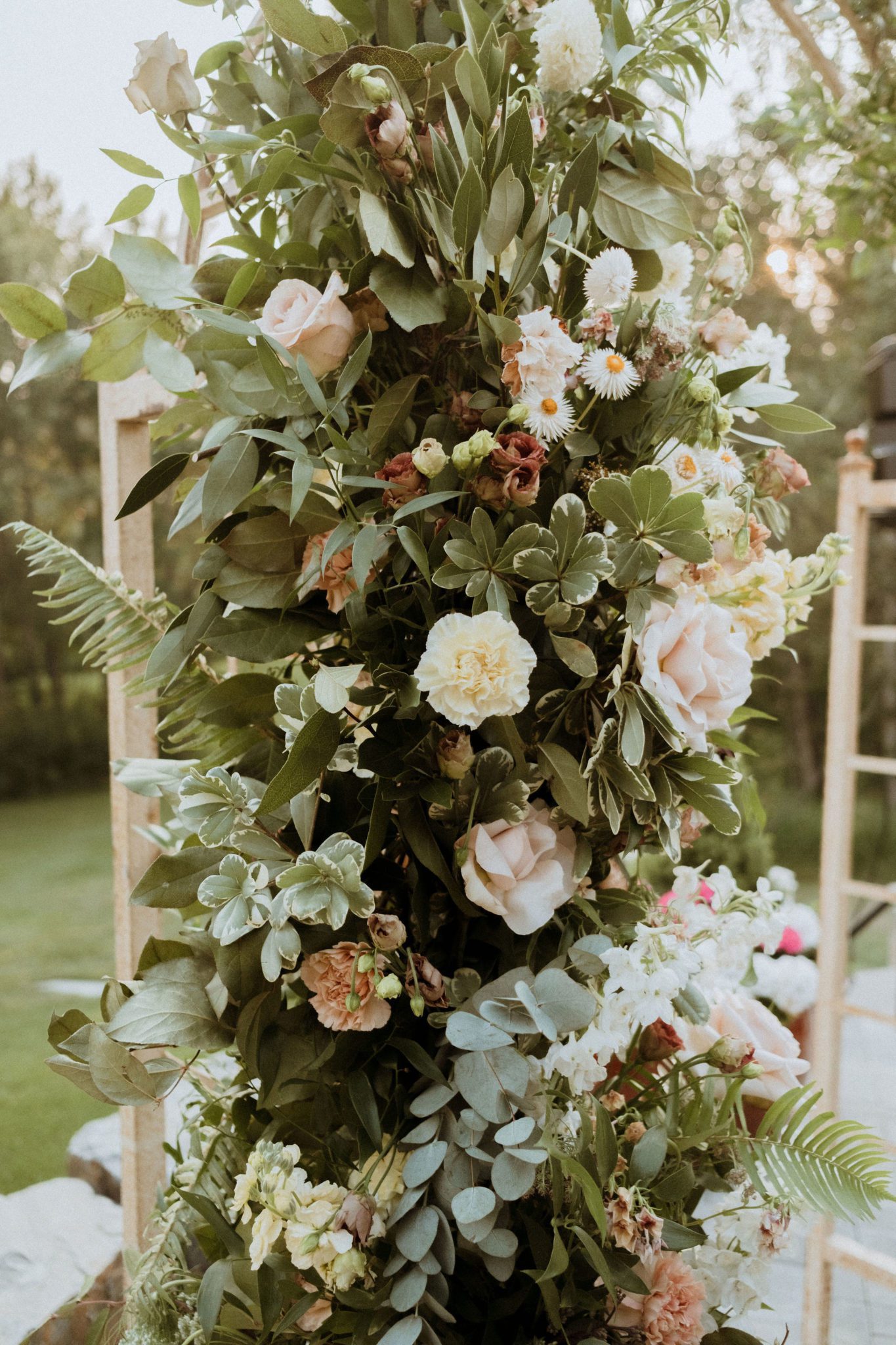 Dramatic floral arch with dusty pink roses at outdoor summer wedding