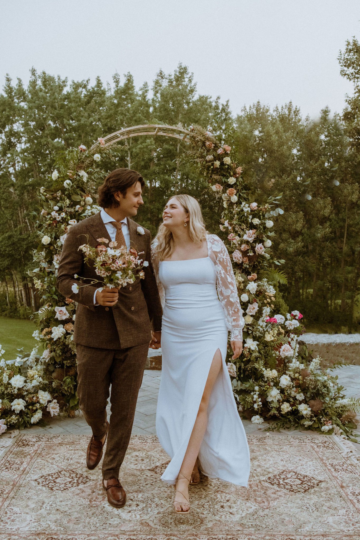 Bridal portraits in front of pink and green dramatic floral arch, dusty pink and green cottage core wedding inspiration, unique wedding attire