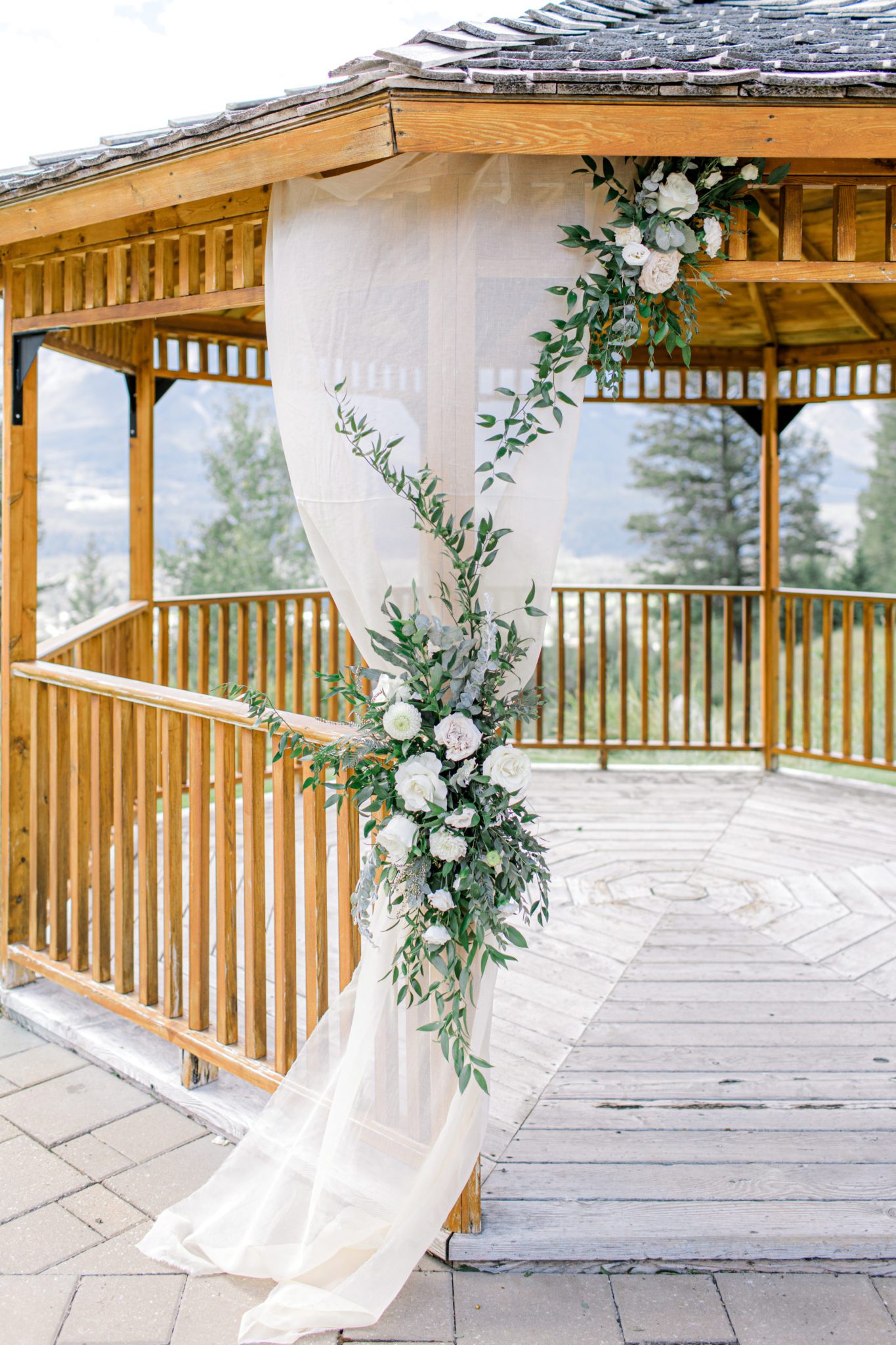 Outdoor wedding gazebo in Canmore, Alberta at Silvertip Resort. Blush and green florals on blush drapery, classic wedding ceremony inspiration. 