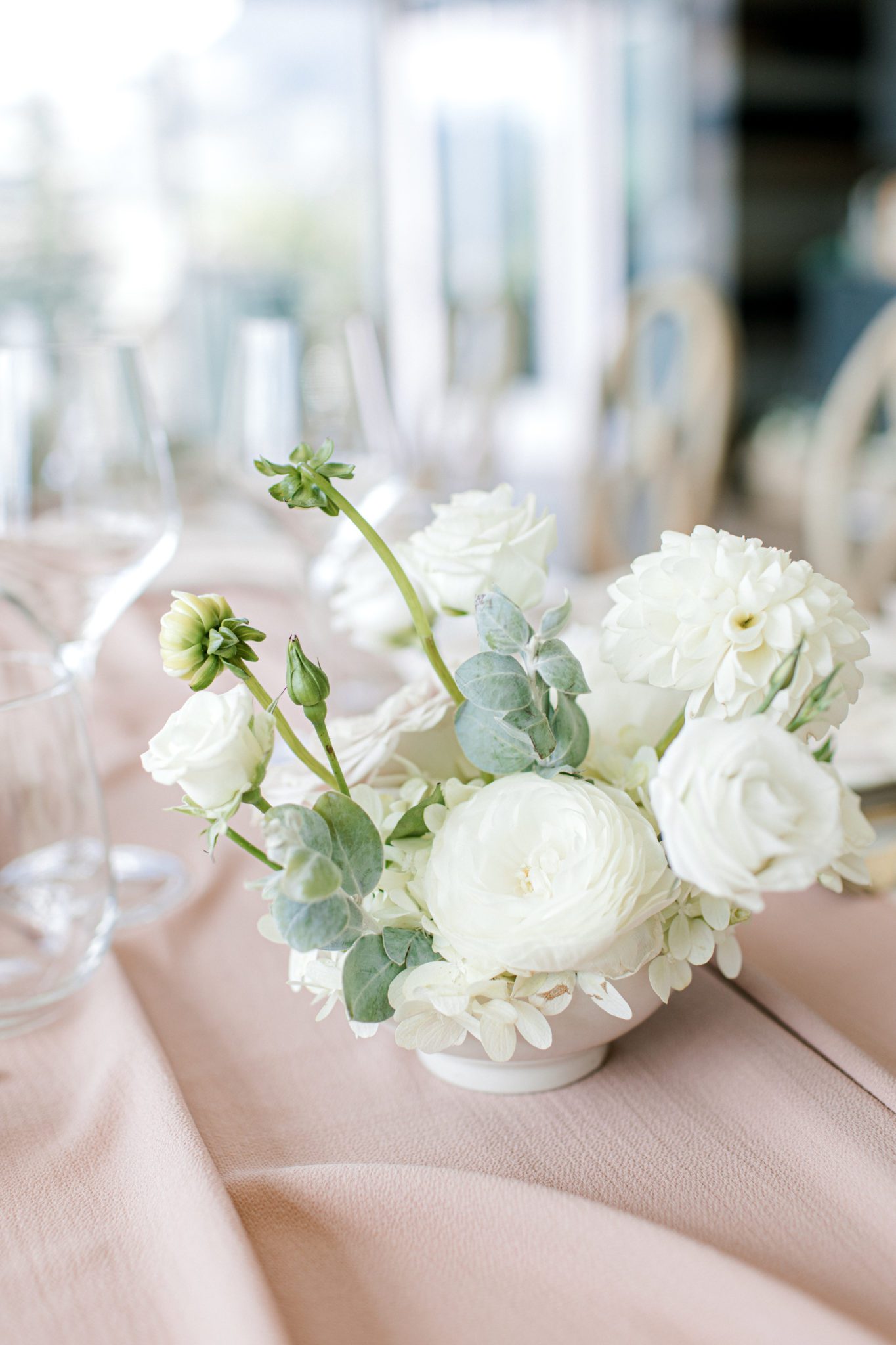 Ivory florals with greenery in this wedding centerpiece with a blush table runner