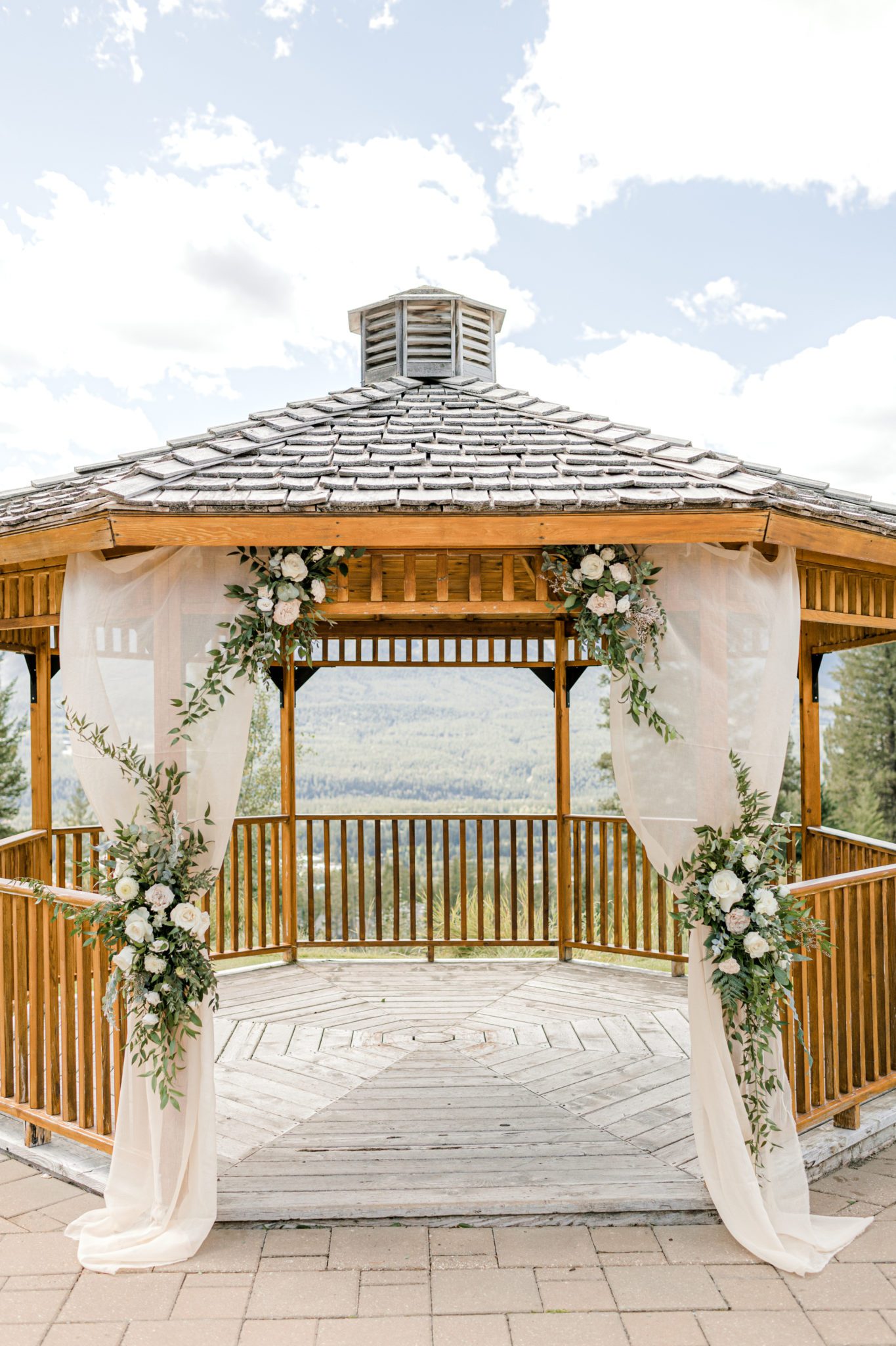 Outdoor wedding gazebo in Canmore, Alberta at Silvertip Resort. Blush and green florals on blush drapery, classic wedding ceremony inspiration. 