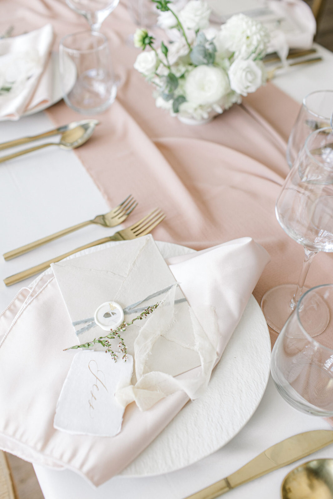 Place setting with gold cutlery, textured ceramic plate, handmade paper envelope, place card with ribbon and calligraphy, beautiful modern yet classic wedding table inspiration
