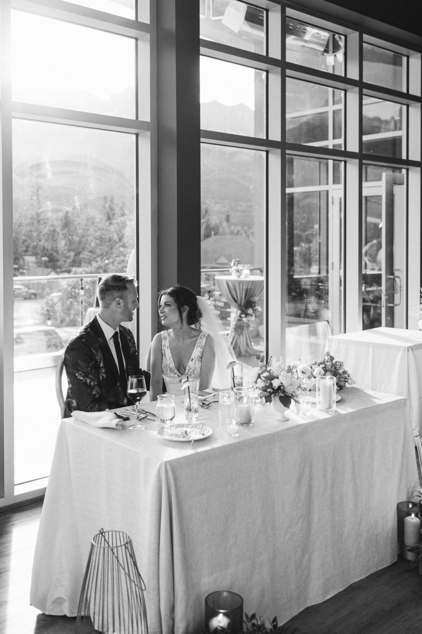 Modern wedding design, black and white wedding photo of bride and groom sitting at their sweetheart table at The Sensory in Canmore Alberta