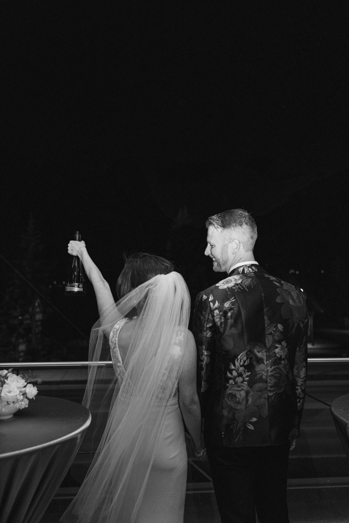Black and white wedding photo of a modern couple celebrating with champagne at their wedding