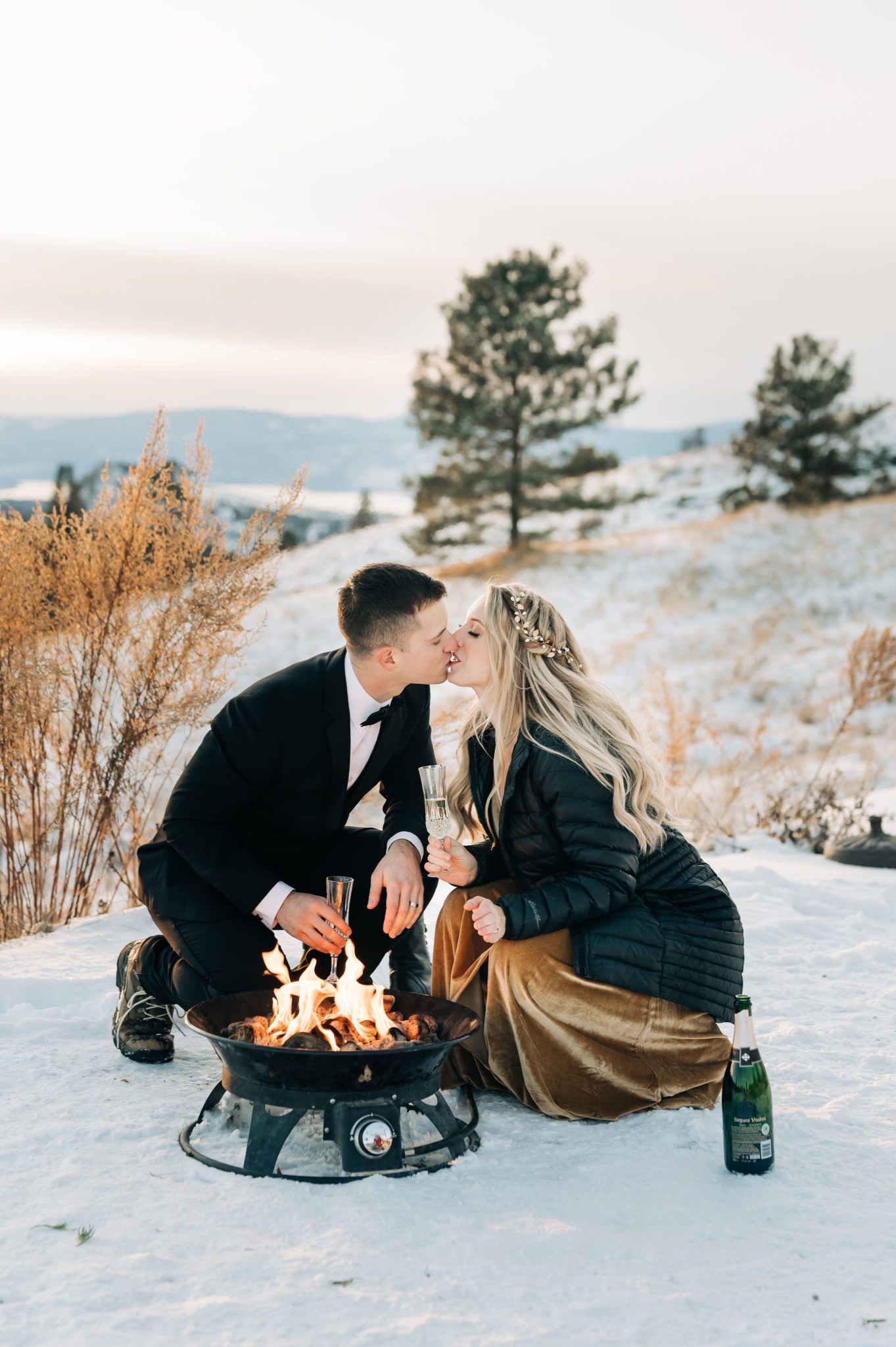 First kiss at the fire in this winter elopement session, champagne and fire pit at outdoor wedding