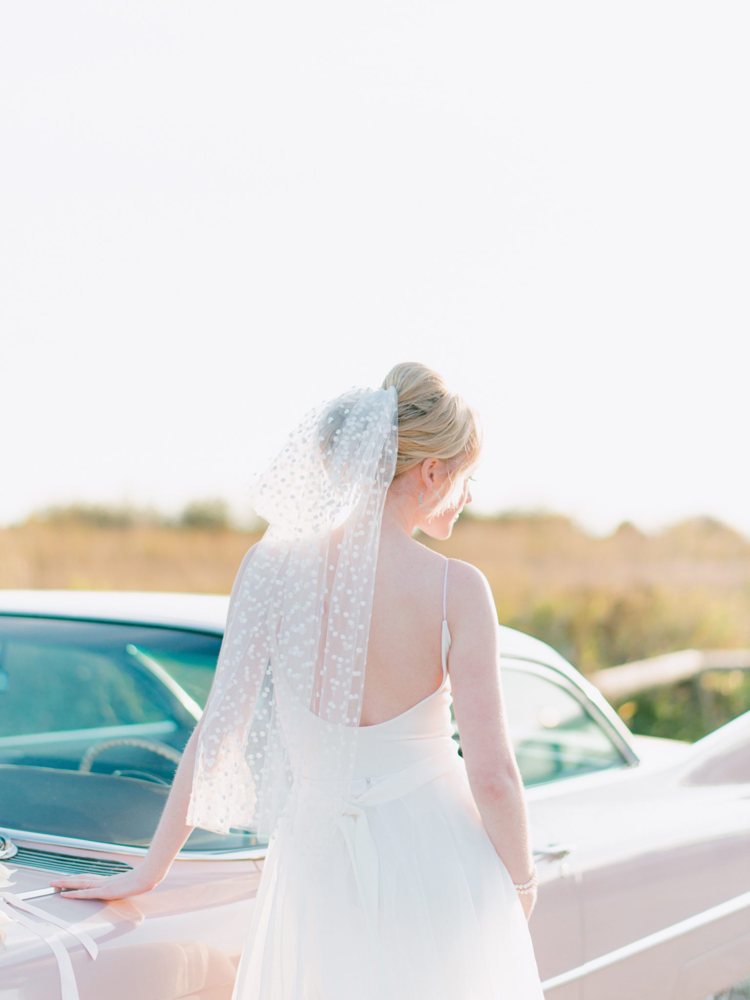 Retro pink Cadillac bridal session features polka dot veil and retro vibes