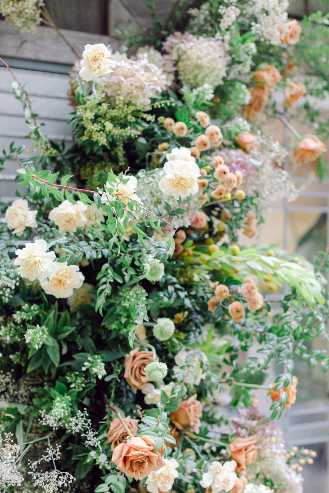 outdoor greenhouse wedding with lush green, cream, pink, and orange florals