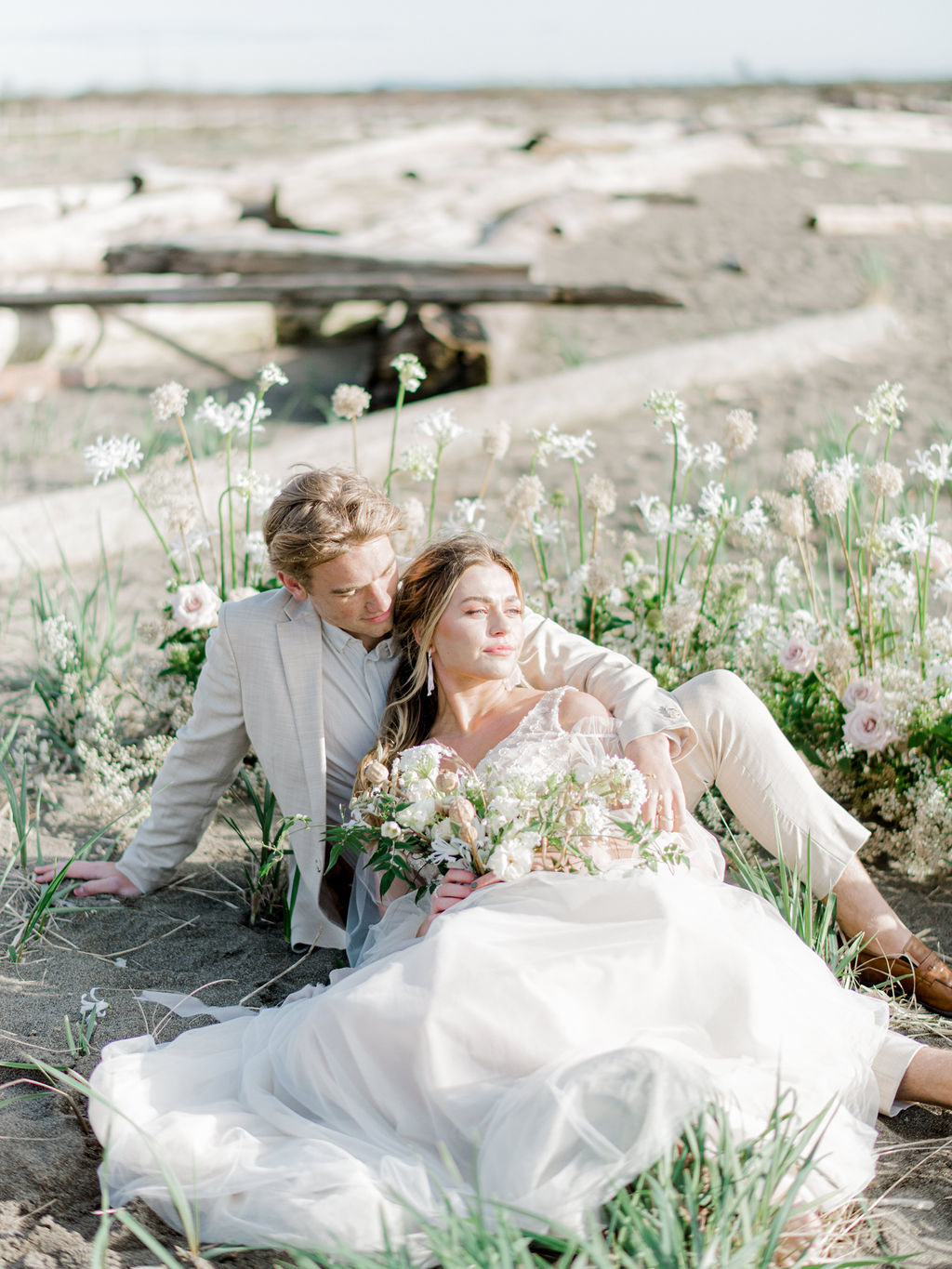 Romantic beach wedding ceremony in Vancouver, British Columbia; Fine art wedding inspiration for an intimate beach wedding, romantic wedding portraits in front of a grounded floral arch with organic greenery and blush and sand coloured florals in front of the ocean