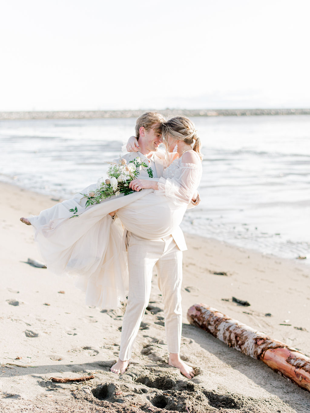 Romantic wedding portraits on the beach in Vancouver, British Columbia;  flowy beach wedding dress with poofy sheer sleeves, beach wedding attire, beach bridal style, bride hair and makeup ideas, low bridal ponytail for an intimate wedding