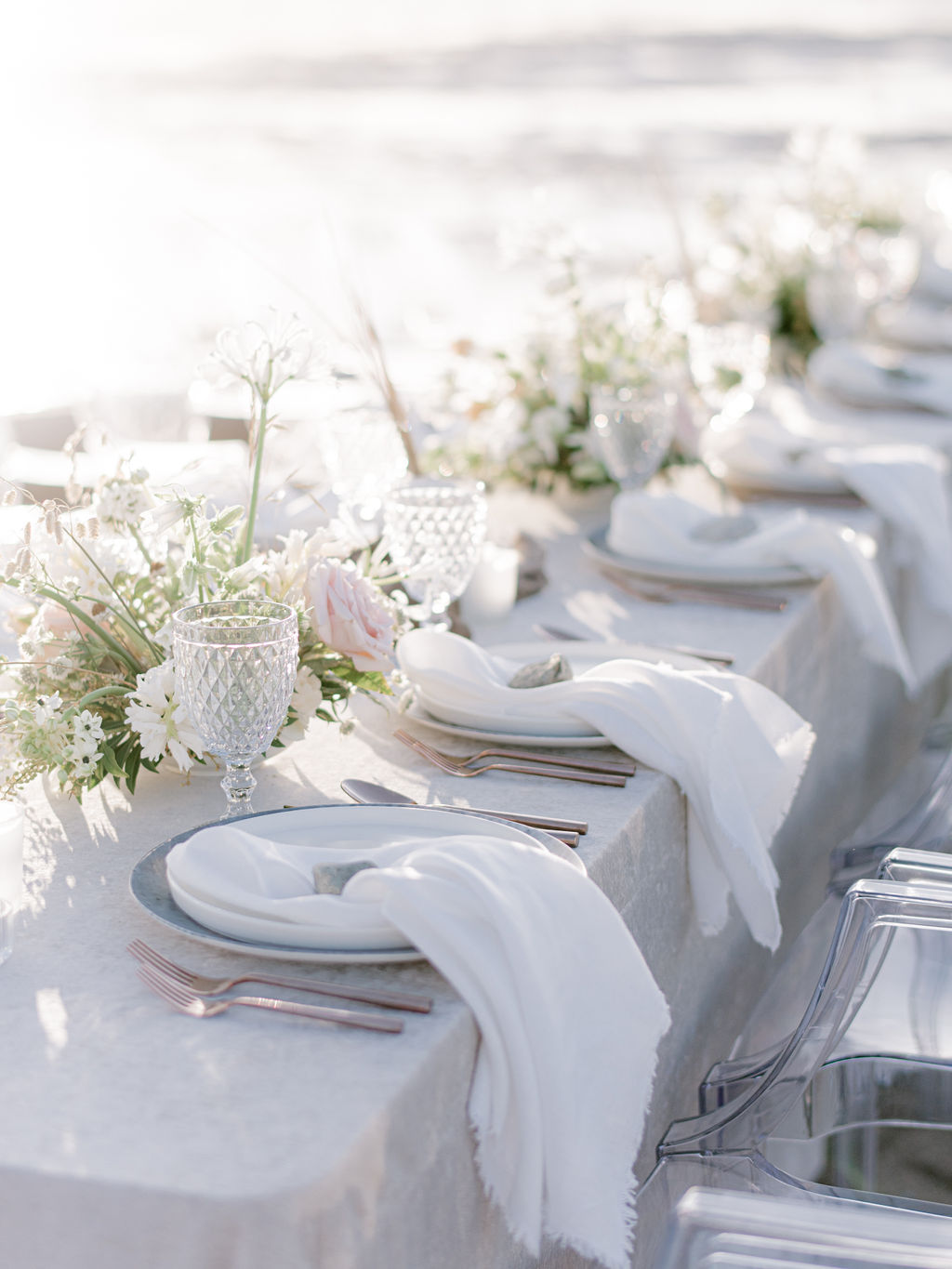 Romantic alfresco dinner along the beach for an intimate Vancouver wedding, spring and summer wedding inspiration in Canada, modern wedding tablescape design with velvet linens, ghost chair seating, and whimsical floral centerpieces in blush and sand tones