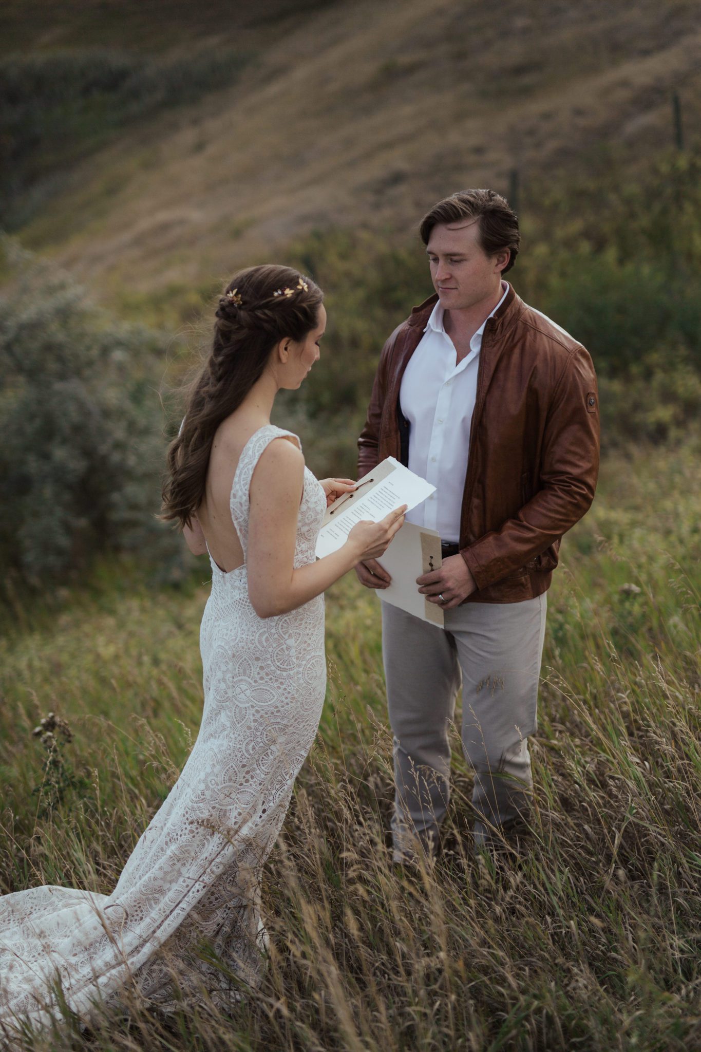 Bride and groom at their intimate vow renewal, reading their vows to each other with Alberta rural countryside as the backdrop, fall vow renewal inspiration. 