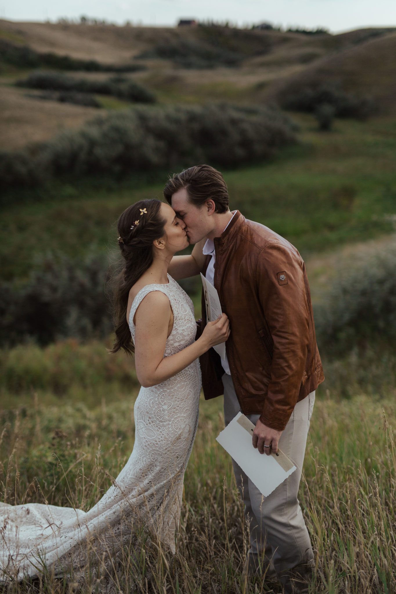Bride and groom share a kiss after reading their vows to each other in a rural Alberta countryside, fall vow renewal inspiration, bride wearing lace-detailed gown.