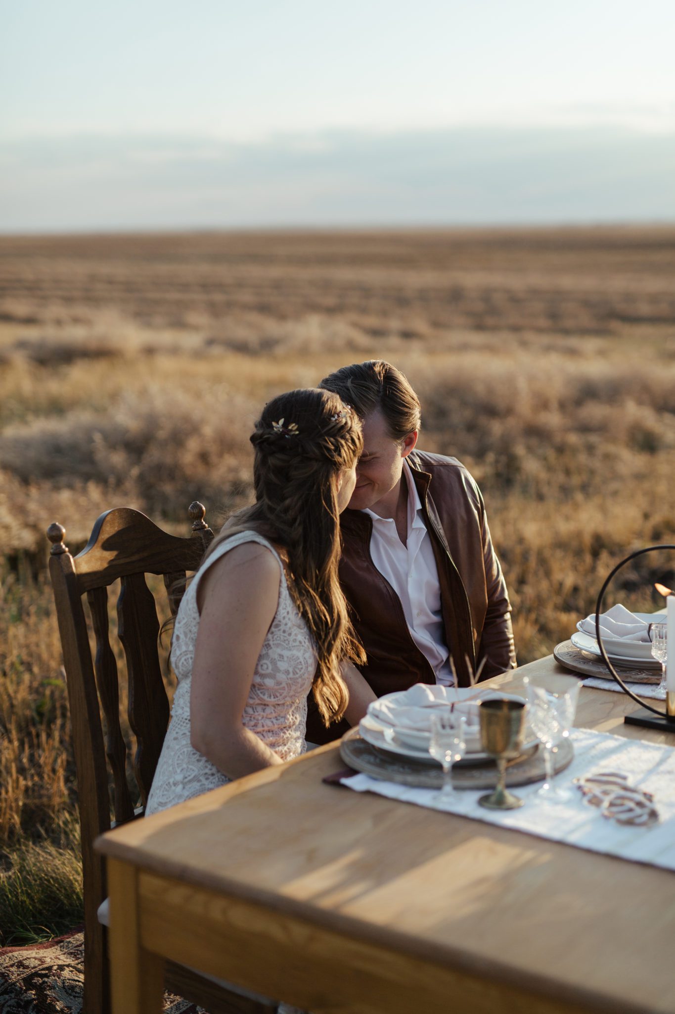 Portrait of bride and groom while sitting at their autumn-inspired sweetheart table, located in the rural Alberta countryside, fall vow renewal inspiration. 