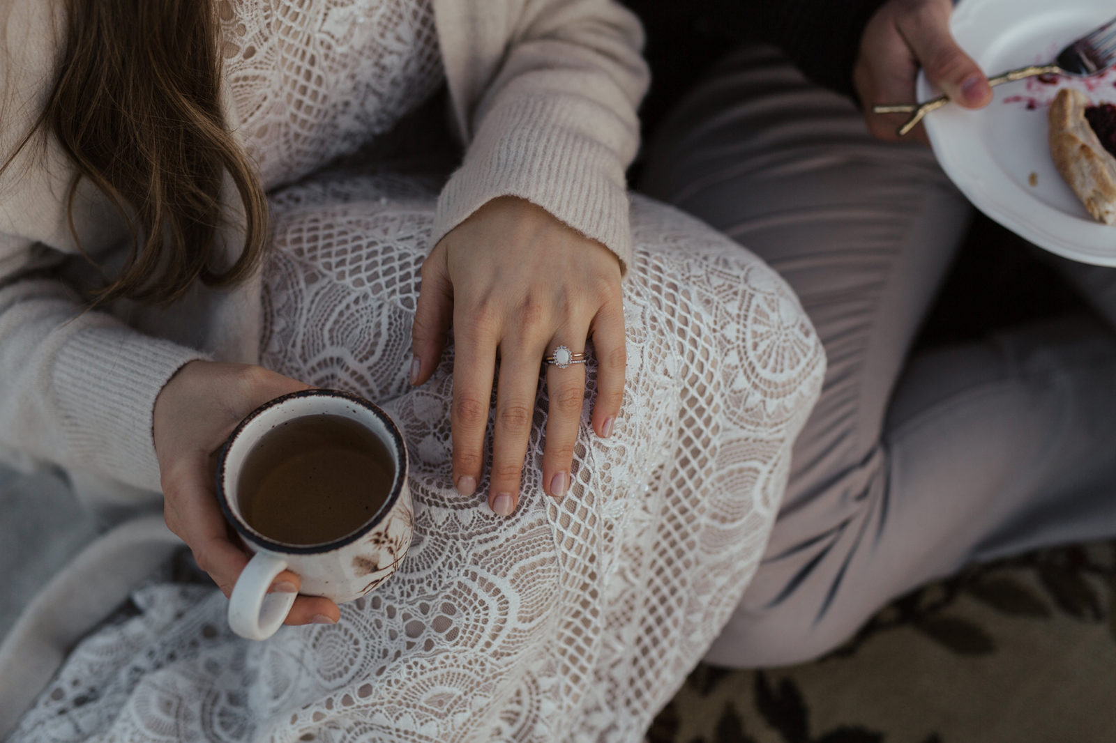 Detailed photo of bride's wedding and engagement ring, while holding a warm drink in a vintage mug. 