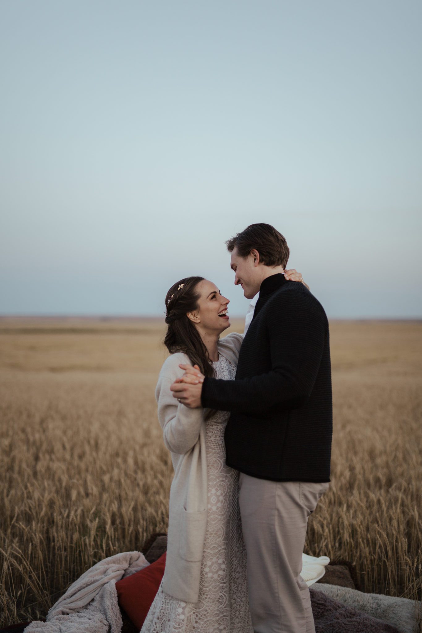 The newlyweds share a first dance in an open field, bride is wearing a lace-detailed gown, fall vow renewal inspiration. 