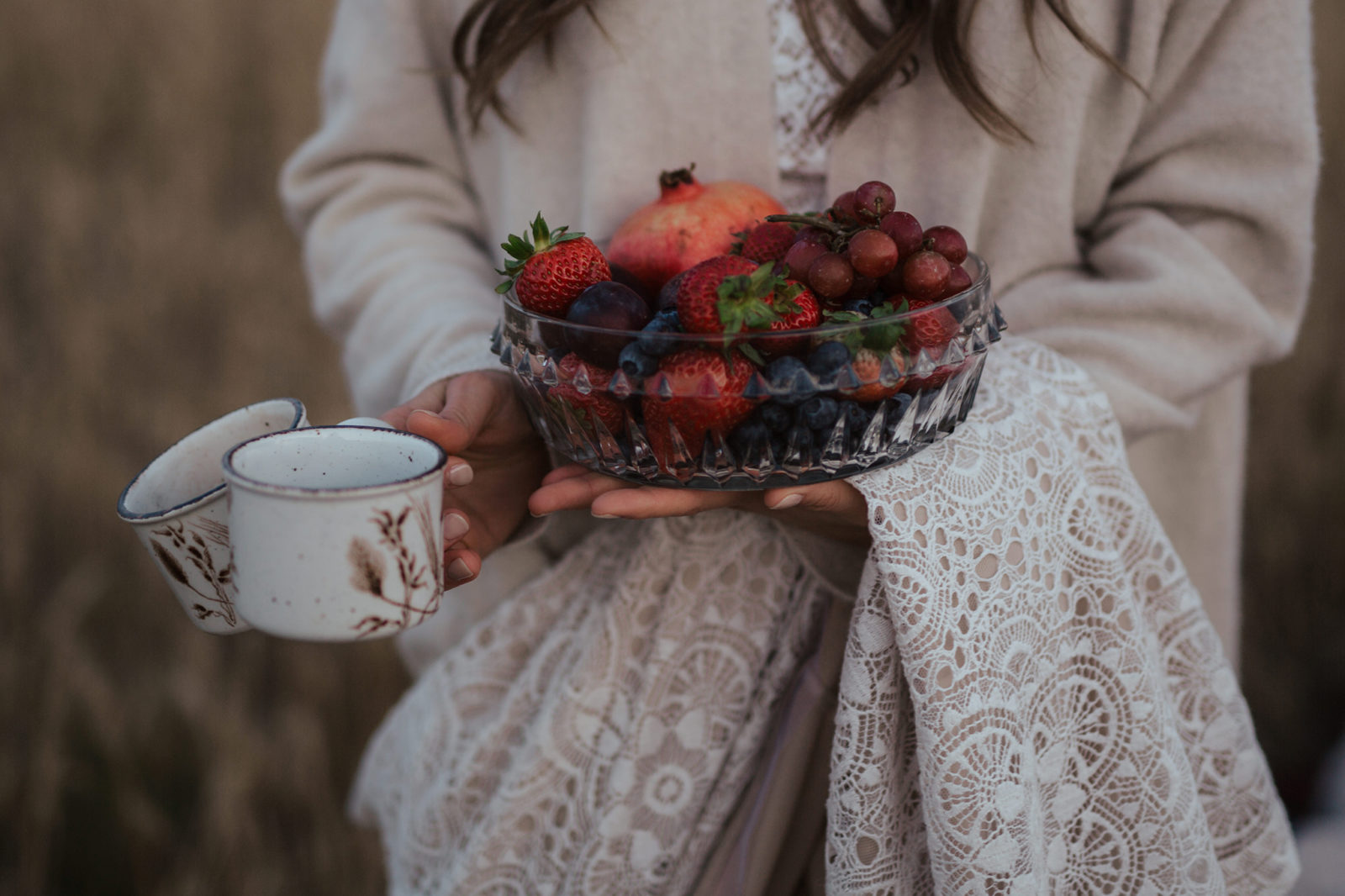 Close up detailed photo of the bride holding fresh berries and hand-painted mugs at their autumn vow renewal. 