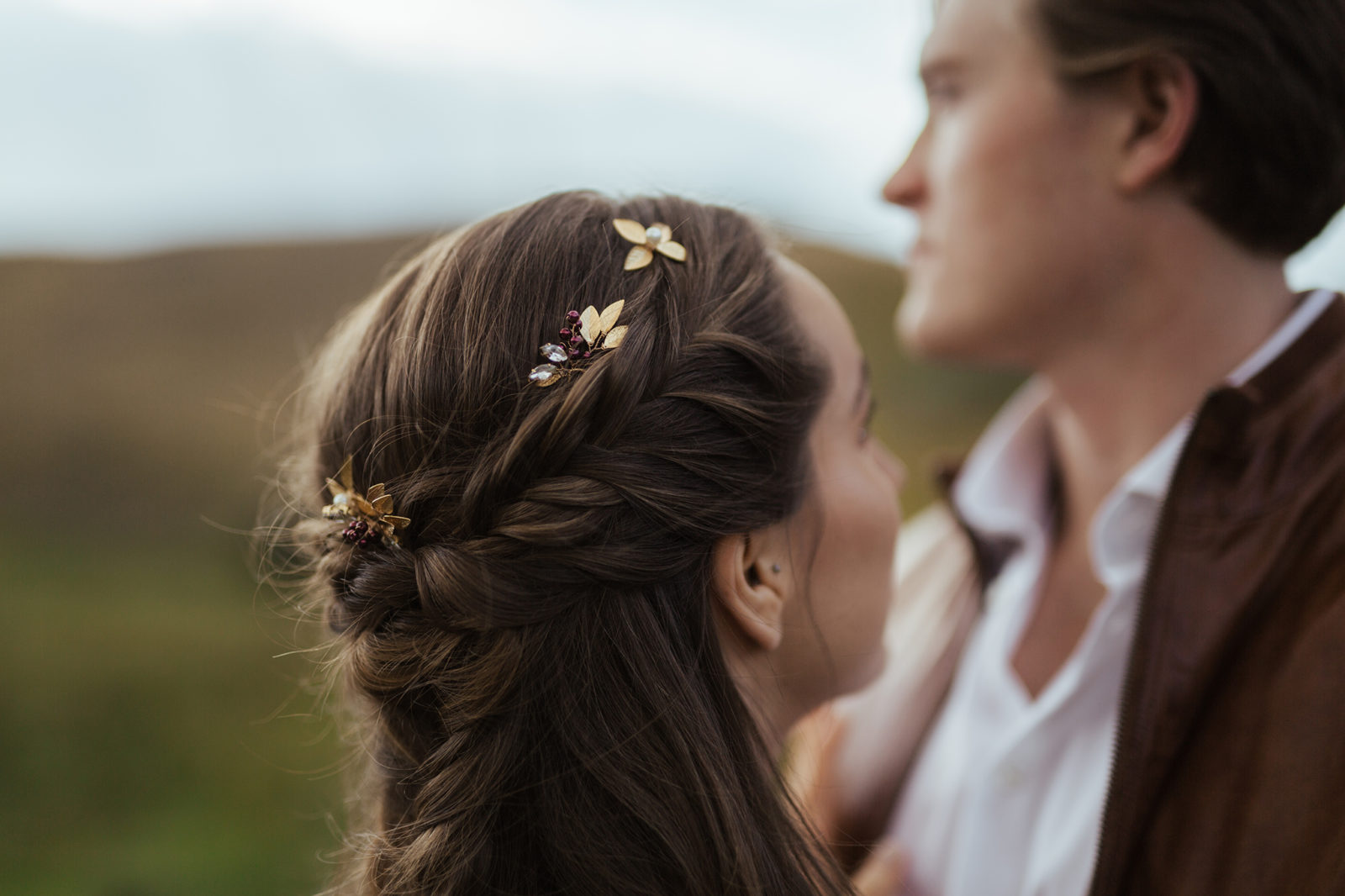 Close up portrait of bride's braided updo and floral hair pieces weaved in. 