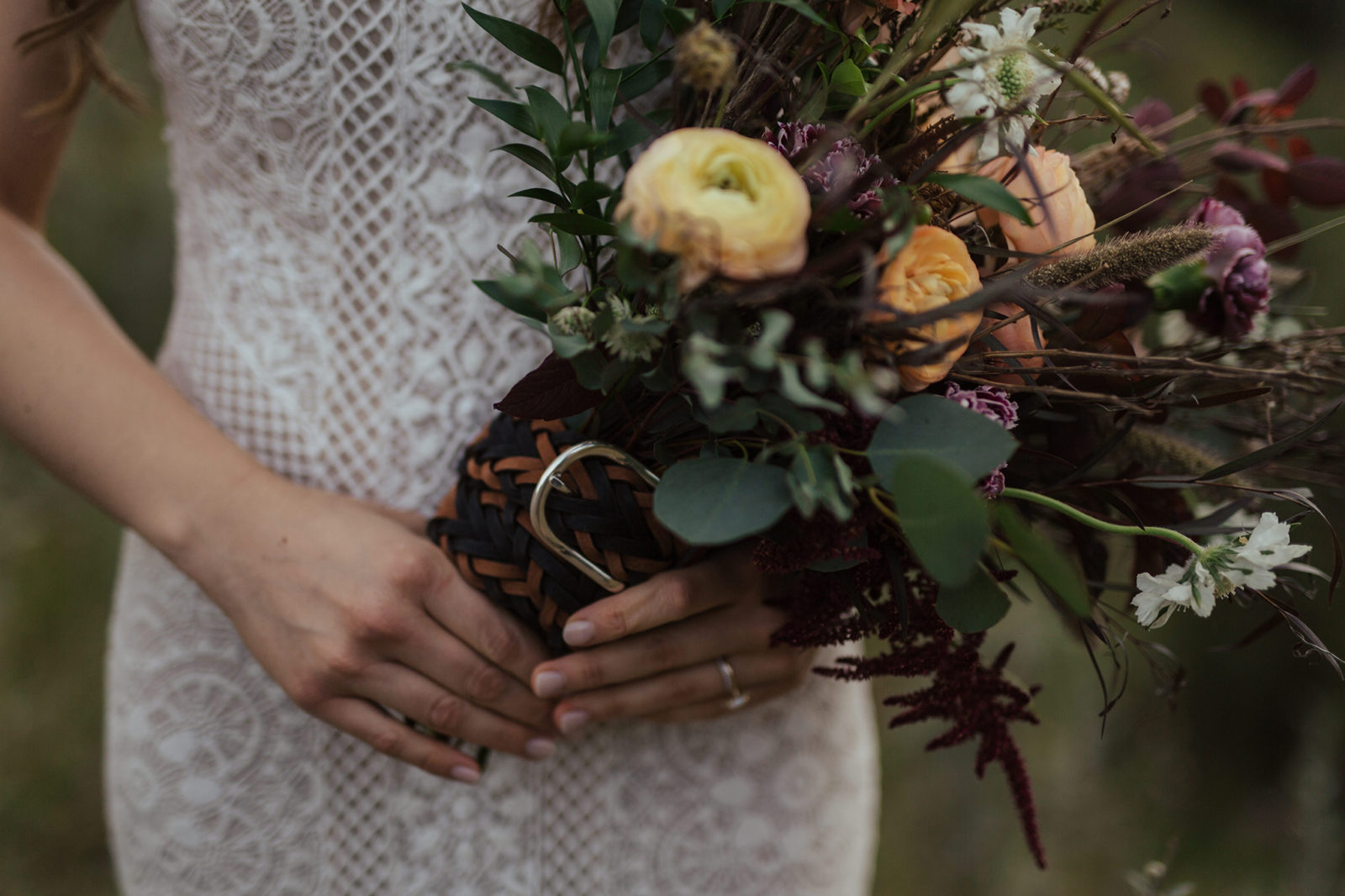 Autumn-inspired bridal bouquet with a variety of textures and colours, featuring bride's lace-detailed gown. 