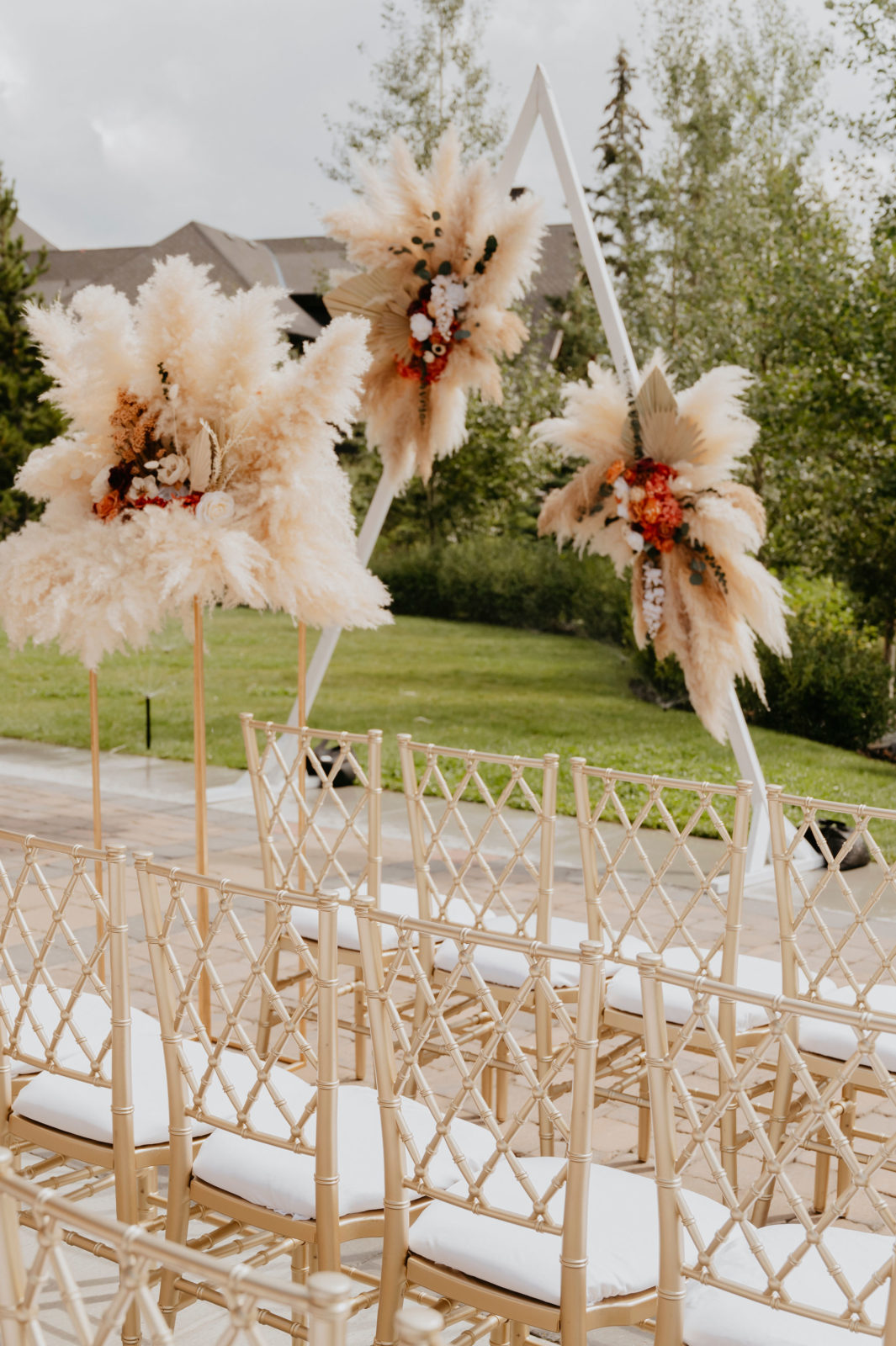 outdoor boho glam wedding ceremony, triangle wedding arch with pampas grass, pampas grass and rustic wedding florals