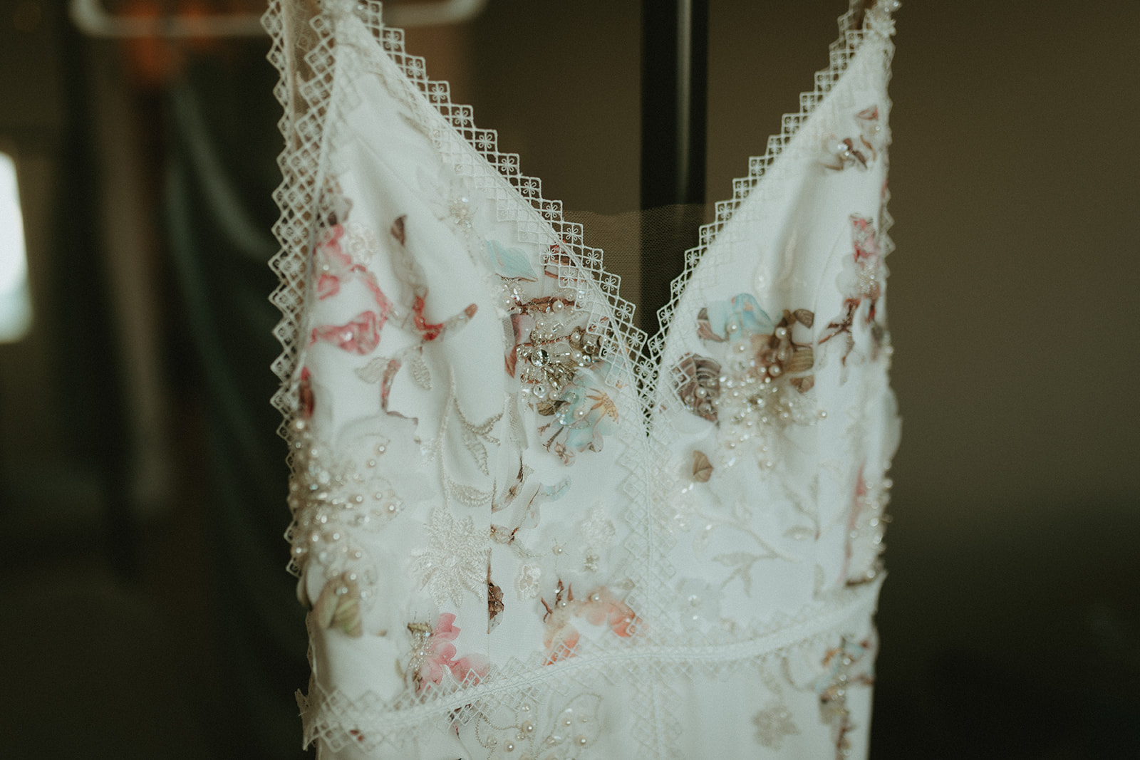 Beaded floral wedding gown hanging while bride gets ready. Non-traditional coloured wedding gown by Savin London. 