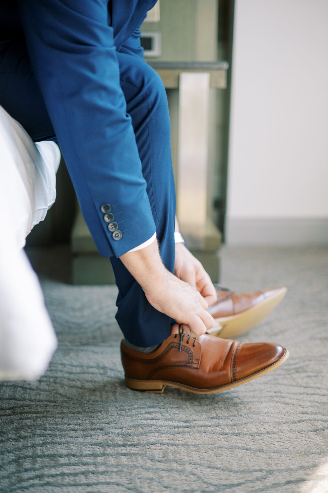 groom laces shoes on wedding day, groom attire