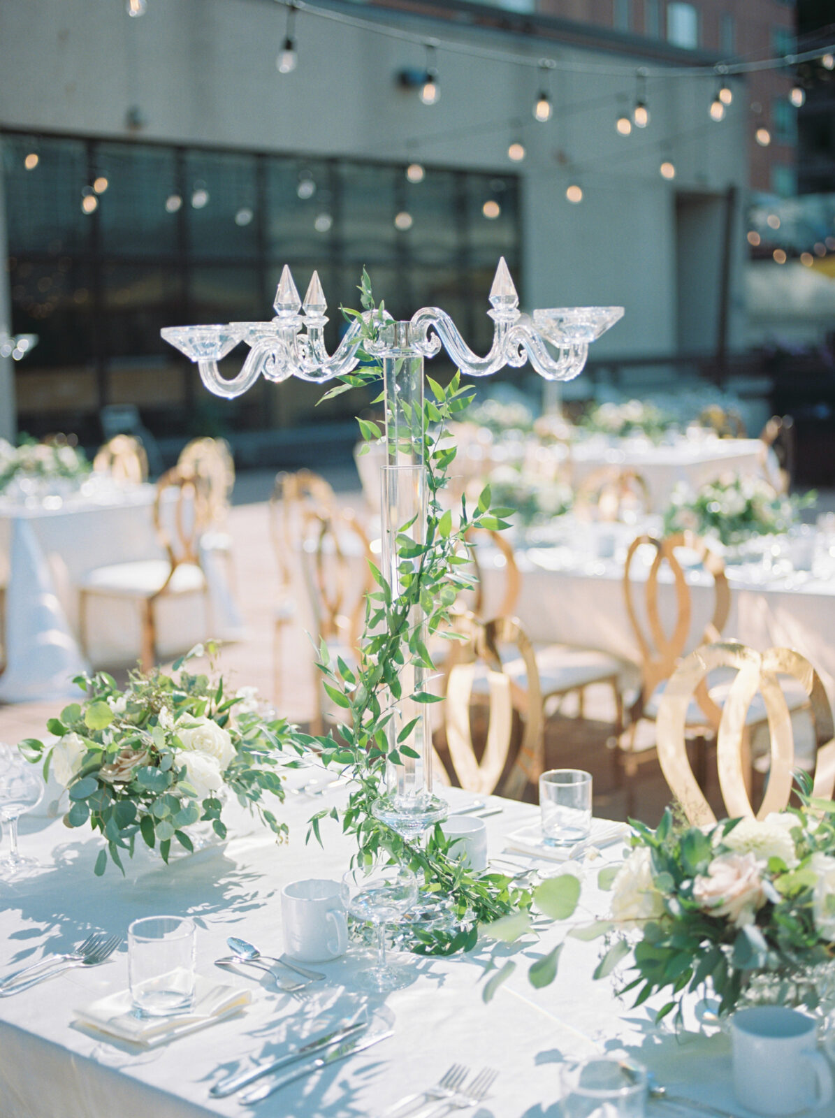 outdoor wedding reception with glass chandelier, gold, and greenery