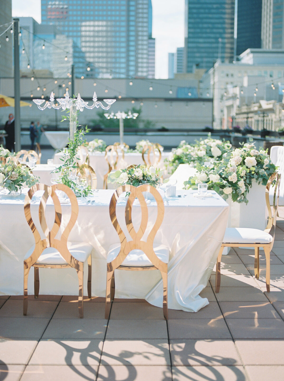 outdoor wedding reception with glass chandelier, gold, and greenery