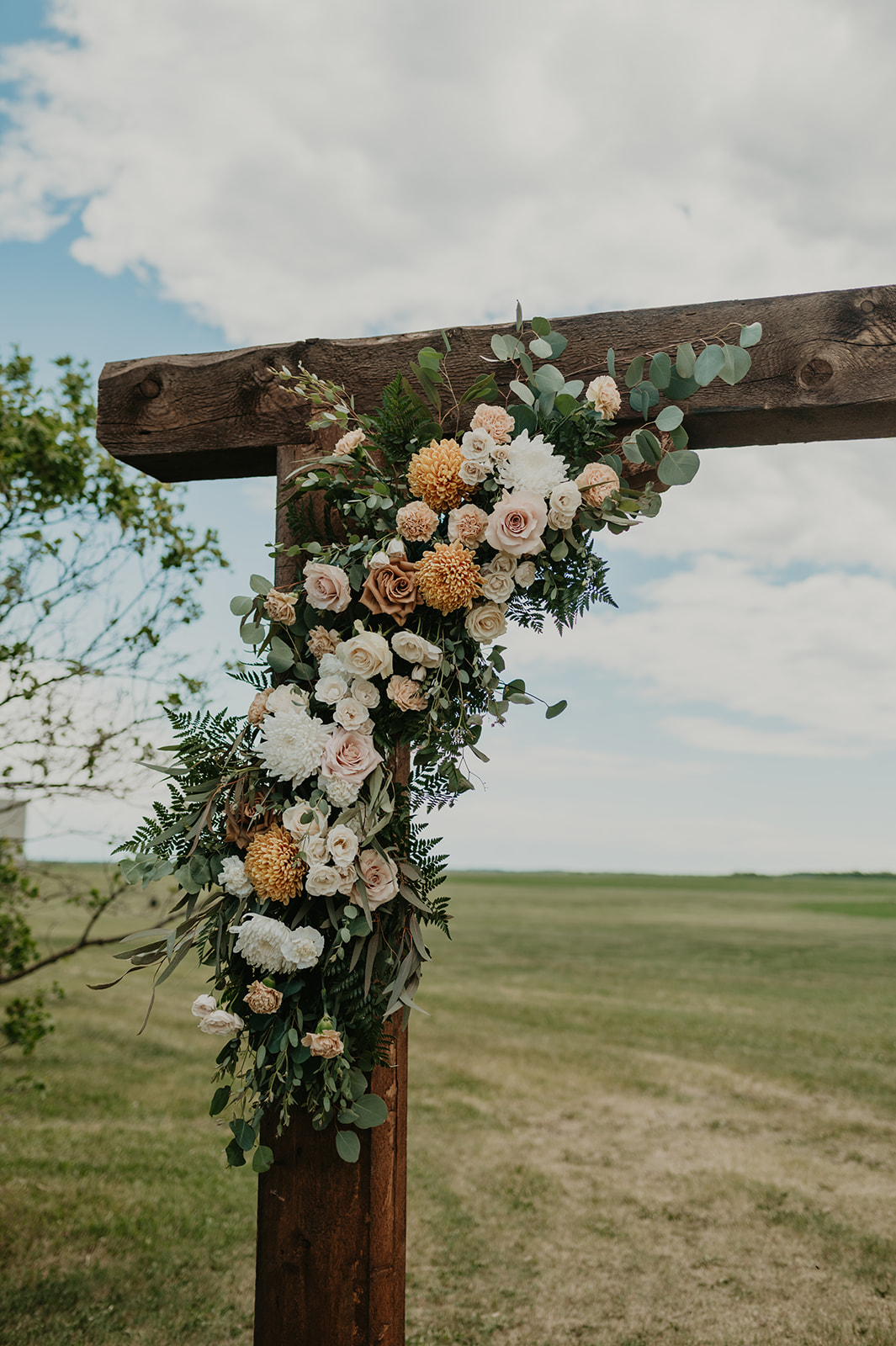 outdoor fall backyard wedding, wedding arch with bright florals, wooden wedding arch