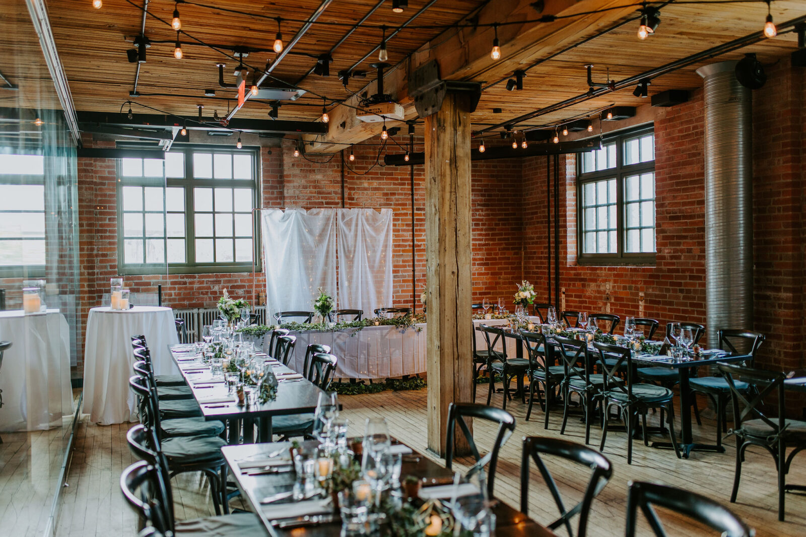 intimate and sentimental fall wedding reception at Char Bar restaurant in Calgary, black chairs and wooden tables in an industrial brick venue