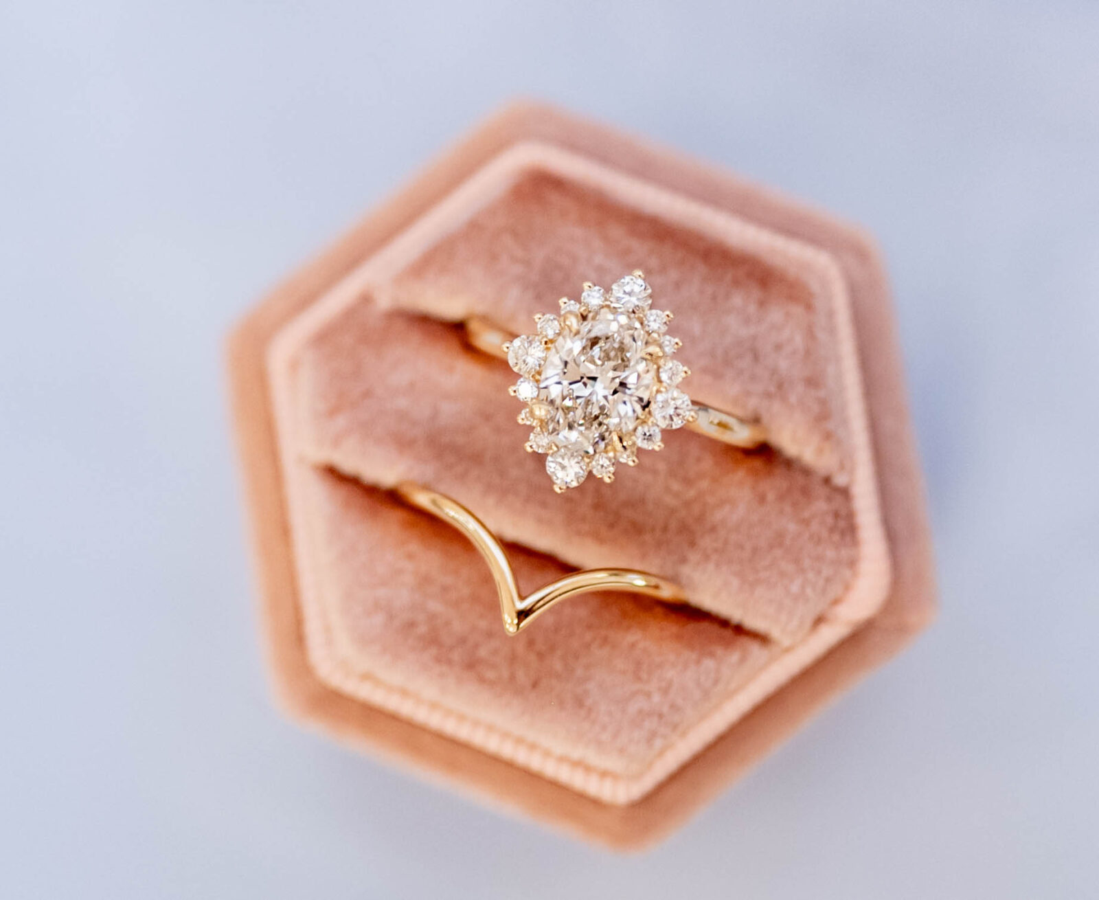 gold engagement ring and wedding band by Alberta Diamond Exchange showcased in light pink velvet ring box, unique oval engagement ring inspiration