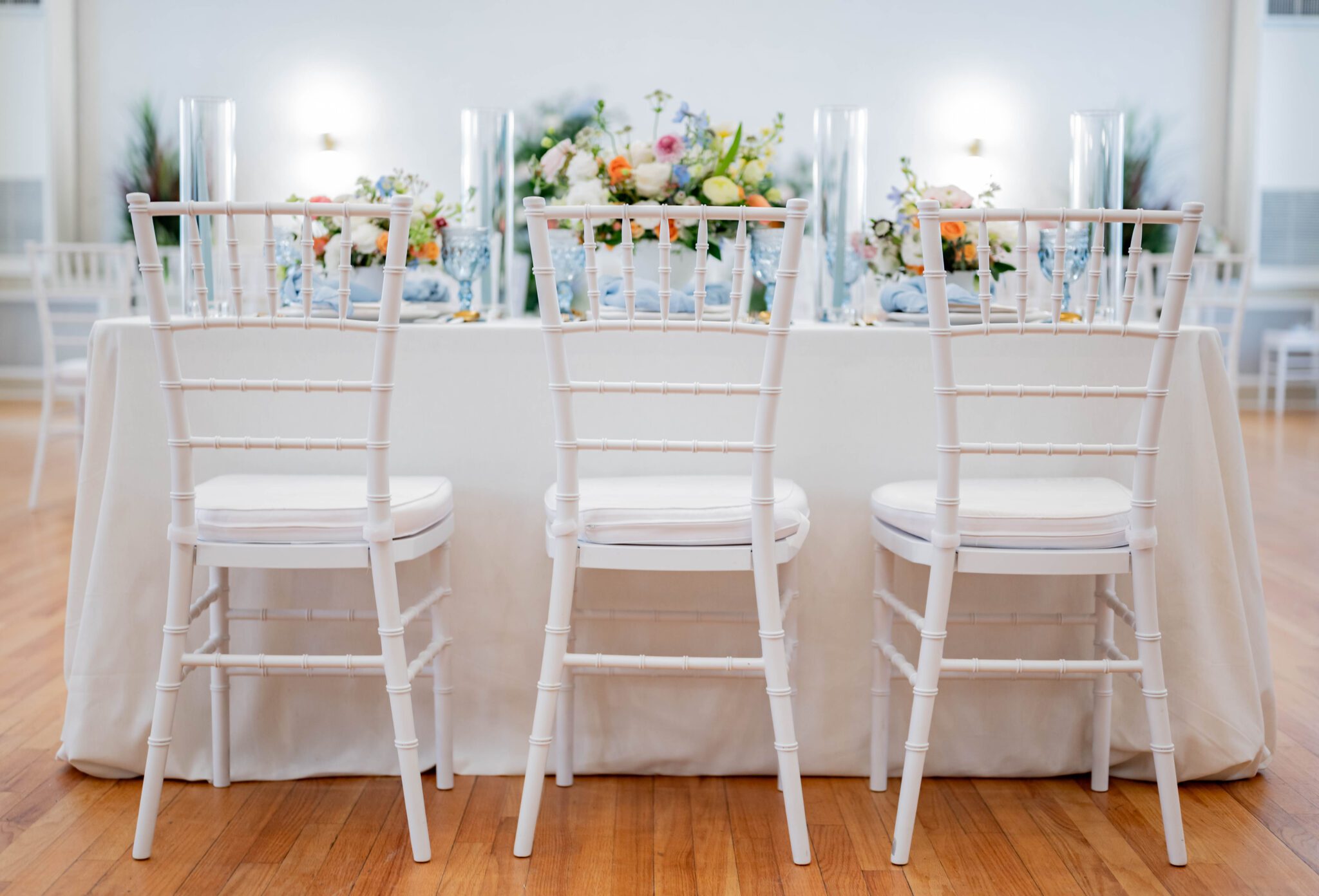 pastel-inspired guest tables with whimsical floral arrangements, white and pastel colour palette with white chiavari guest chairs creating a light and airy atmosphere
