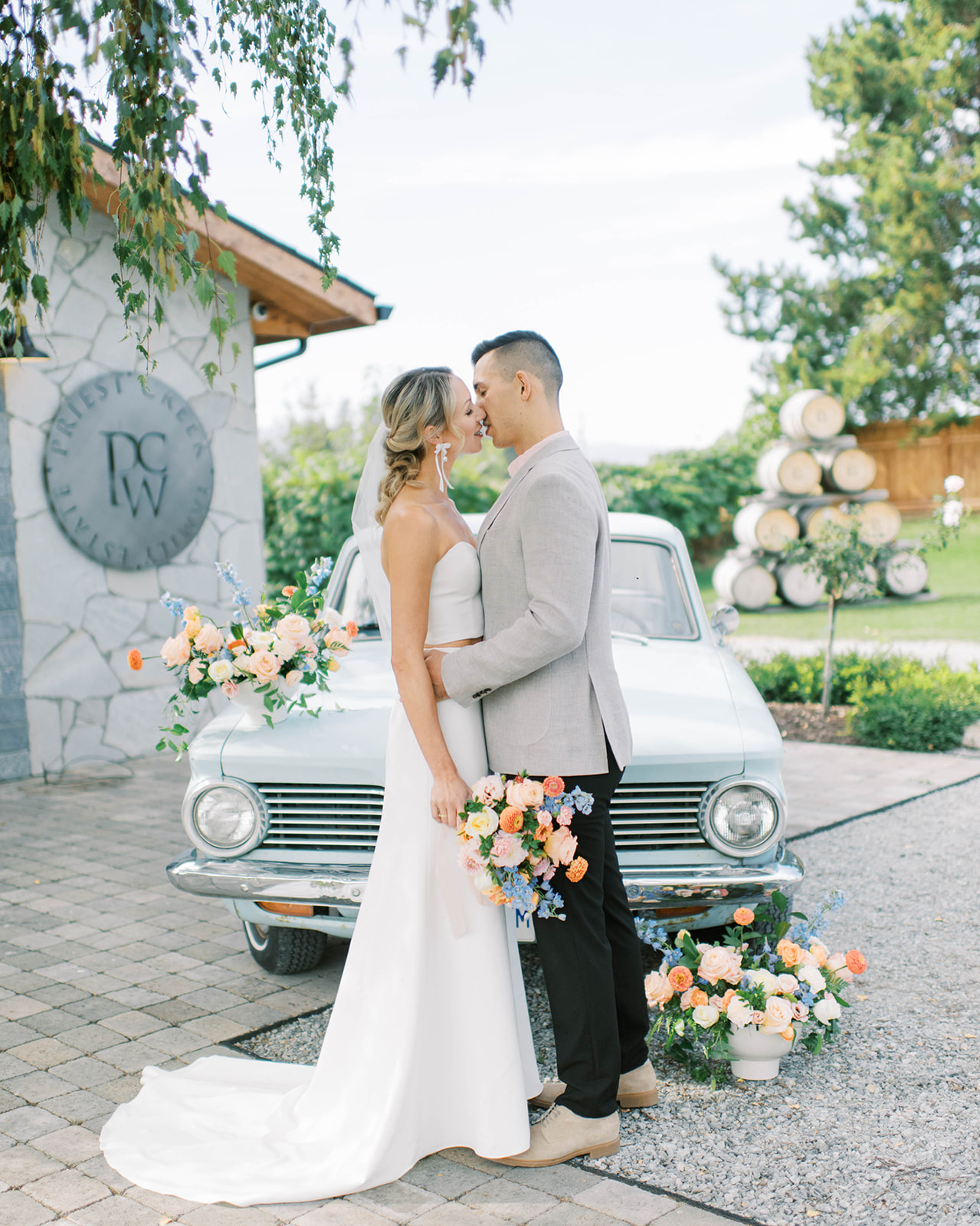 Okanagan winery wedding venue inspiration, Kelowna Wedding Photographer, bride and groom portrait with bride holding summer bouquet of orange, pink and blue florals