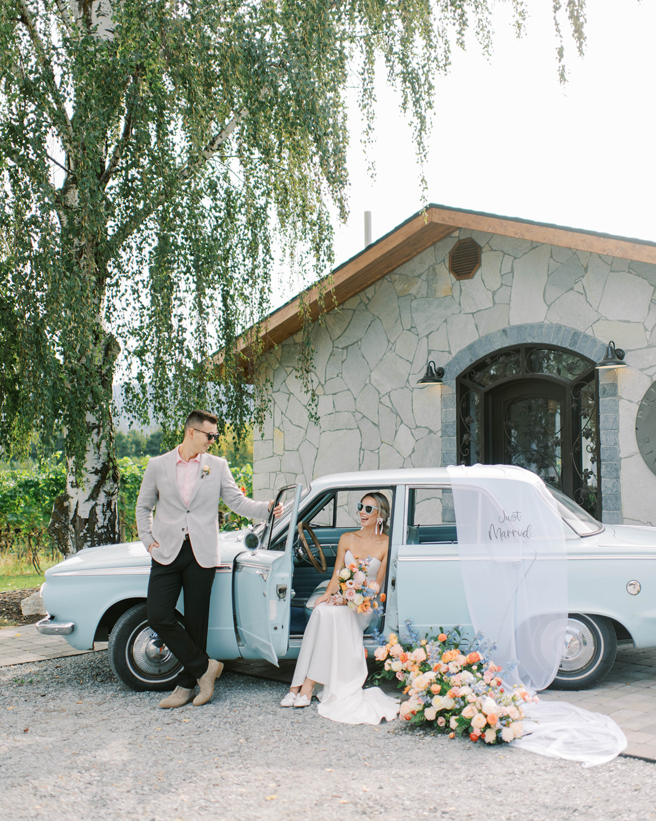 Vintage car rental from Mabel Mae for weddings showcasing beautiful blue wedding inspiration with summer wedding florals, ideas for summer wedding attire for groom, bride and groom smiling bringing warmth and joy to their summer wedding