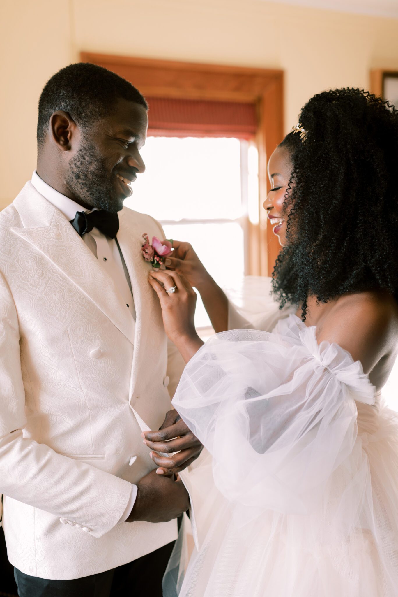 Bride pinning boutonnière on groom, couples portraits in Wateron hotel room, fall floral inspiration 
