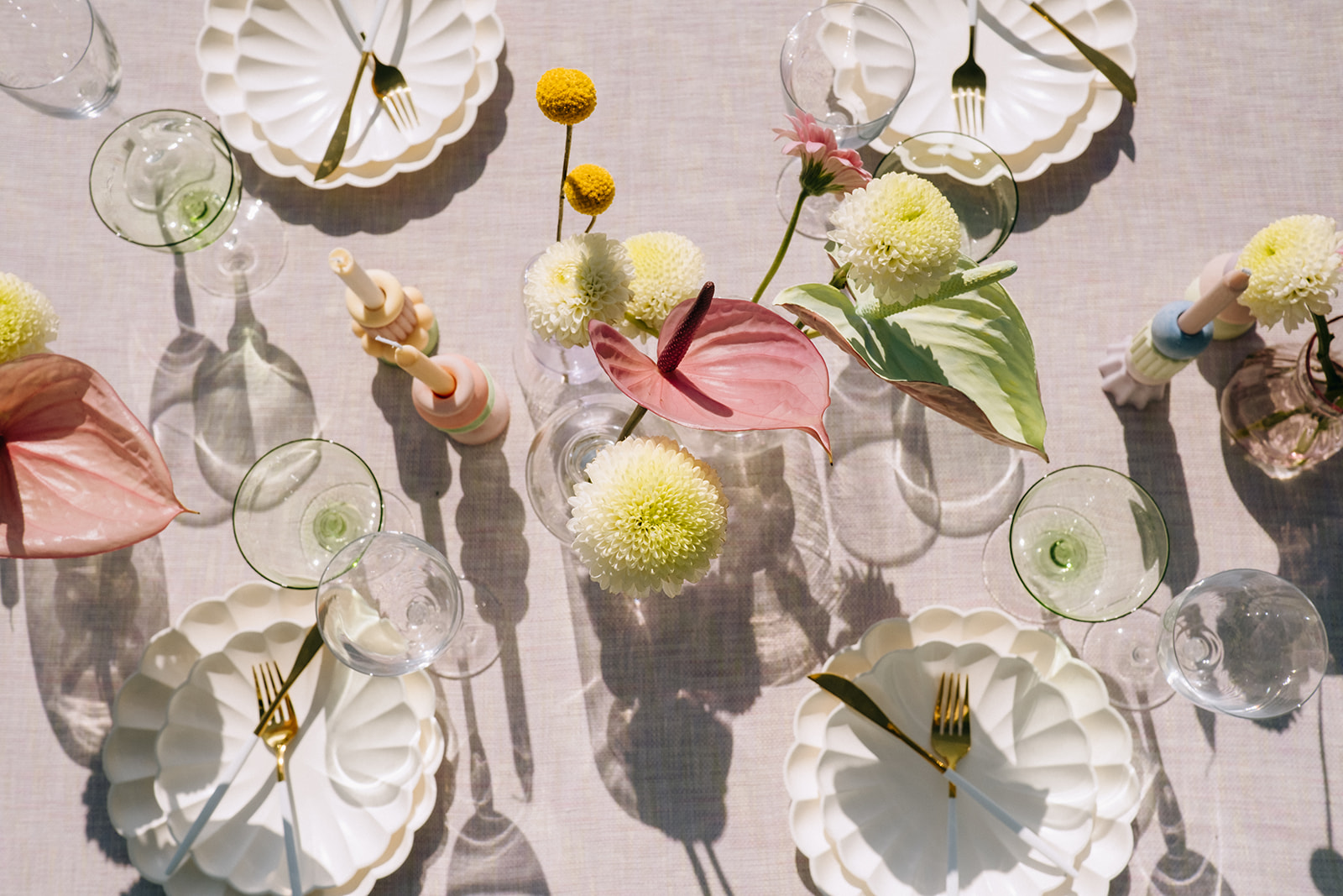 chartreuse and neon floral centrepieces by Hen and Chicks for a vibrant and summery combination, multiple unique vases in clear glass and pastel ceramics holding florals on a wedding guest table, pastel pink linen tablecloth ideas  
