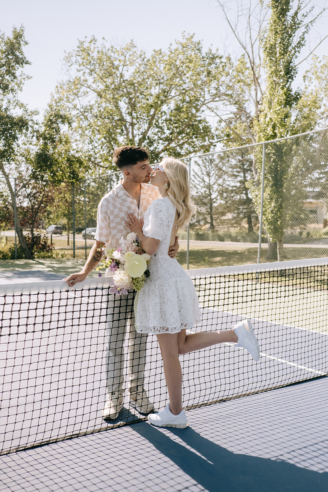 Modern runaway bride sporting white bridal sneakers in couples portraits, tennis-themed wedding portrait inspiration, relaxed and casual groom attire in neutral tones of beige and tan