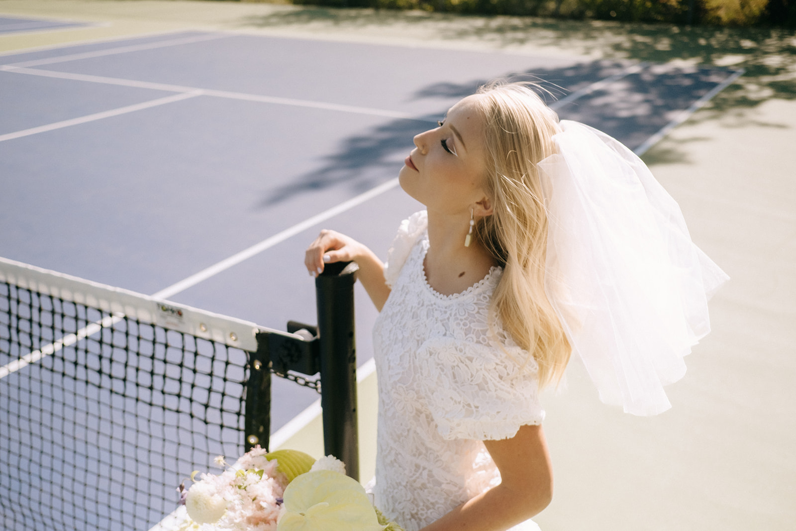 sporty summer bridal style, sporty bridal inspiration, summer bride ideas, summer bridal outfits, open-back white lace wedding dress for outdoor elopement, bride wearing casual short veil for her tennis-themed wedding