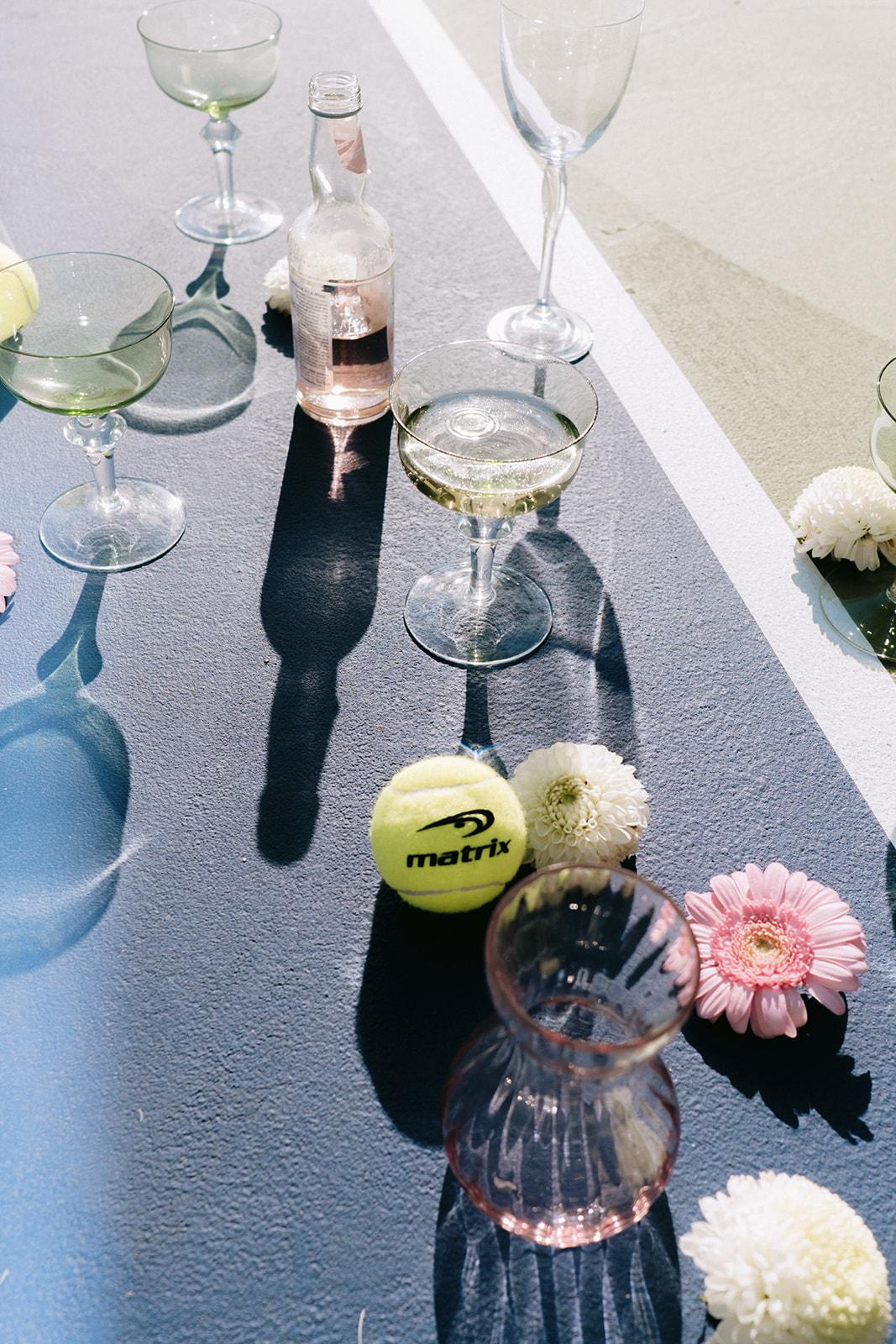 Unique tennis-themed wedding inspiration, chartreuse coup and pastel pink glassware featured in alternative flat lay photo, summery florals in pastel pink and white for wedding details photo