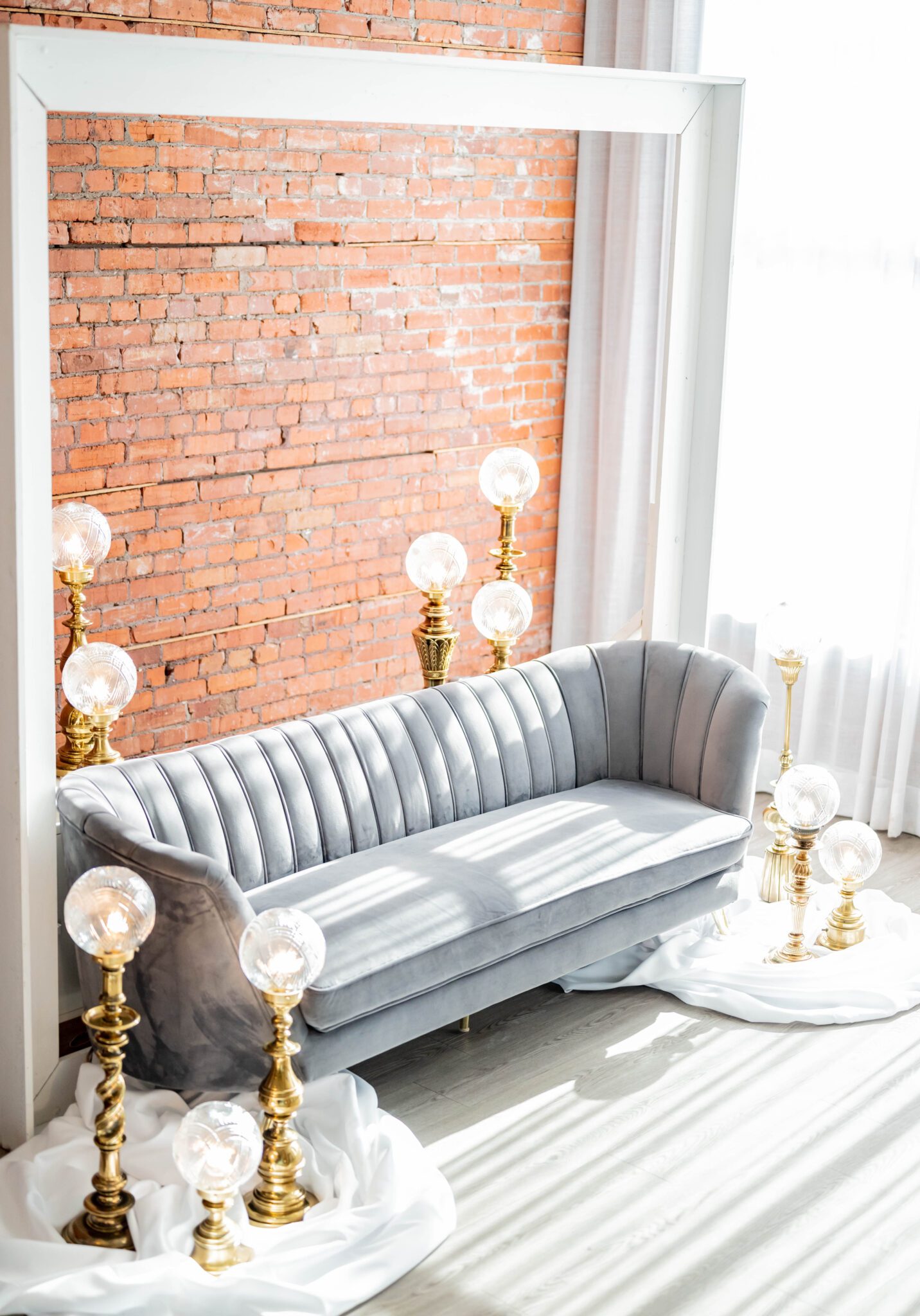 vintage gold light posts with round glass surround a grey velvet couch in front of a brick wall for wedding photos, timeless wedding venue in Calgary, Alberta, vintage wedding ideas 