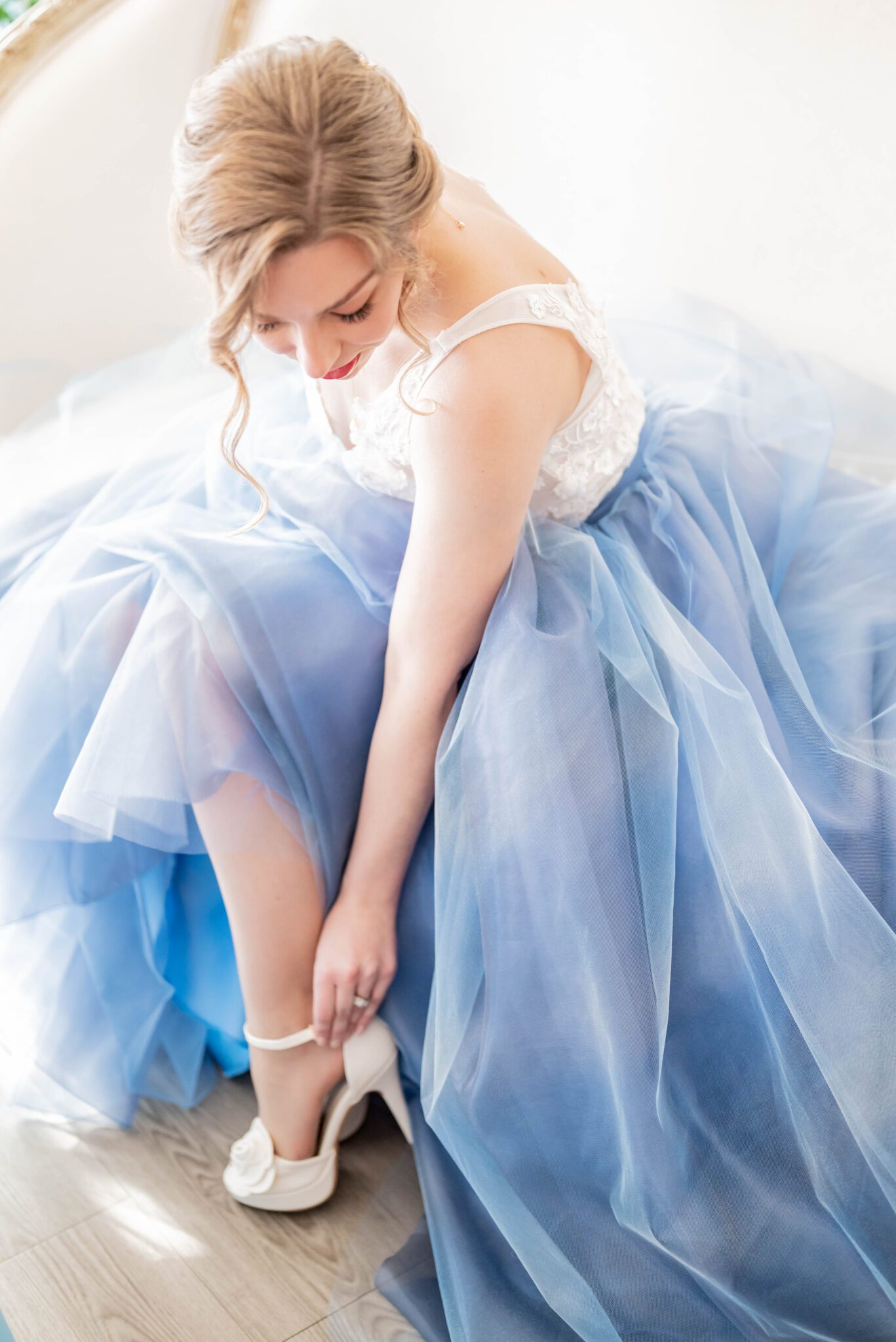 Bride putting on white bridal heels in getting ready photo, two-toned white lace and baby blue organza wedding dress inspiration by Catalina Del Angel Designs, romantic and feminine bridal fashion